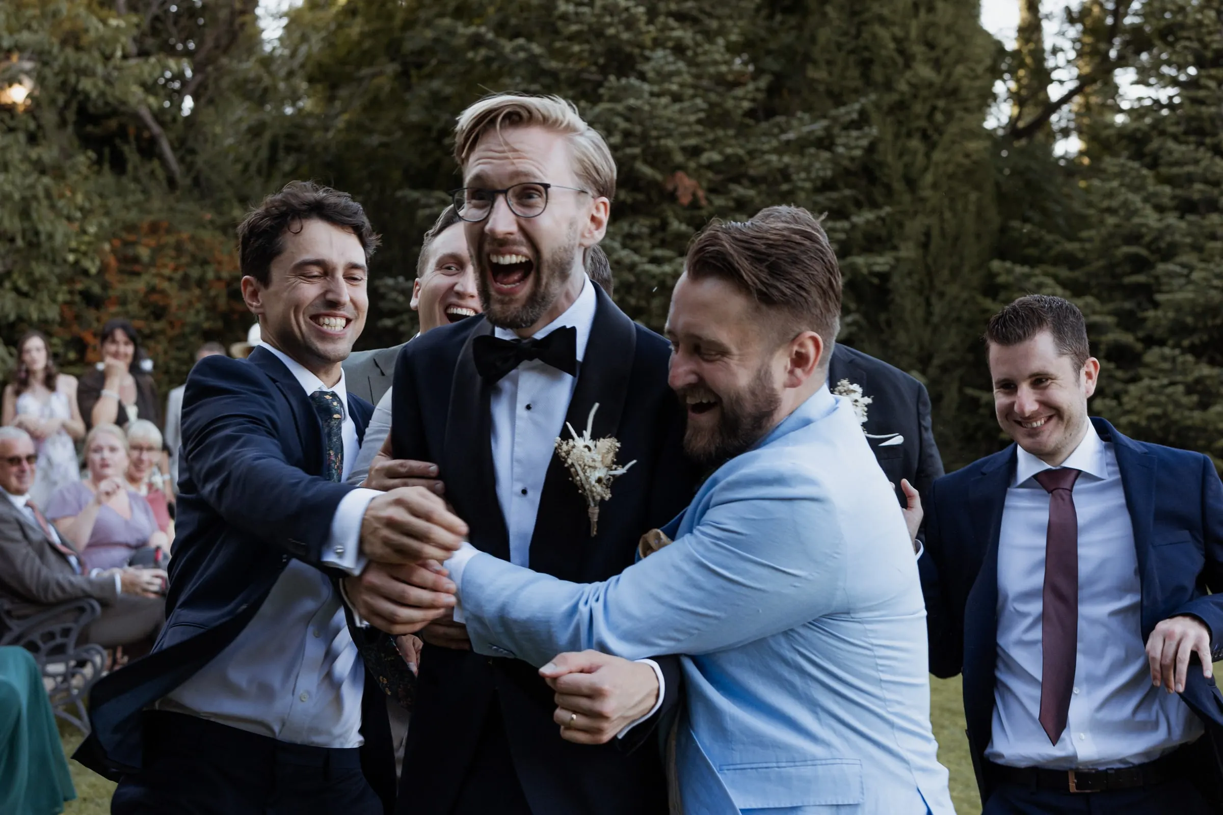 Groomsmen hugging the groom and cheering after the ceremony