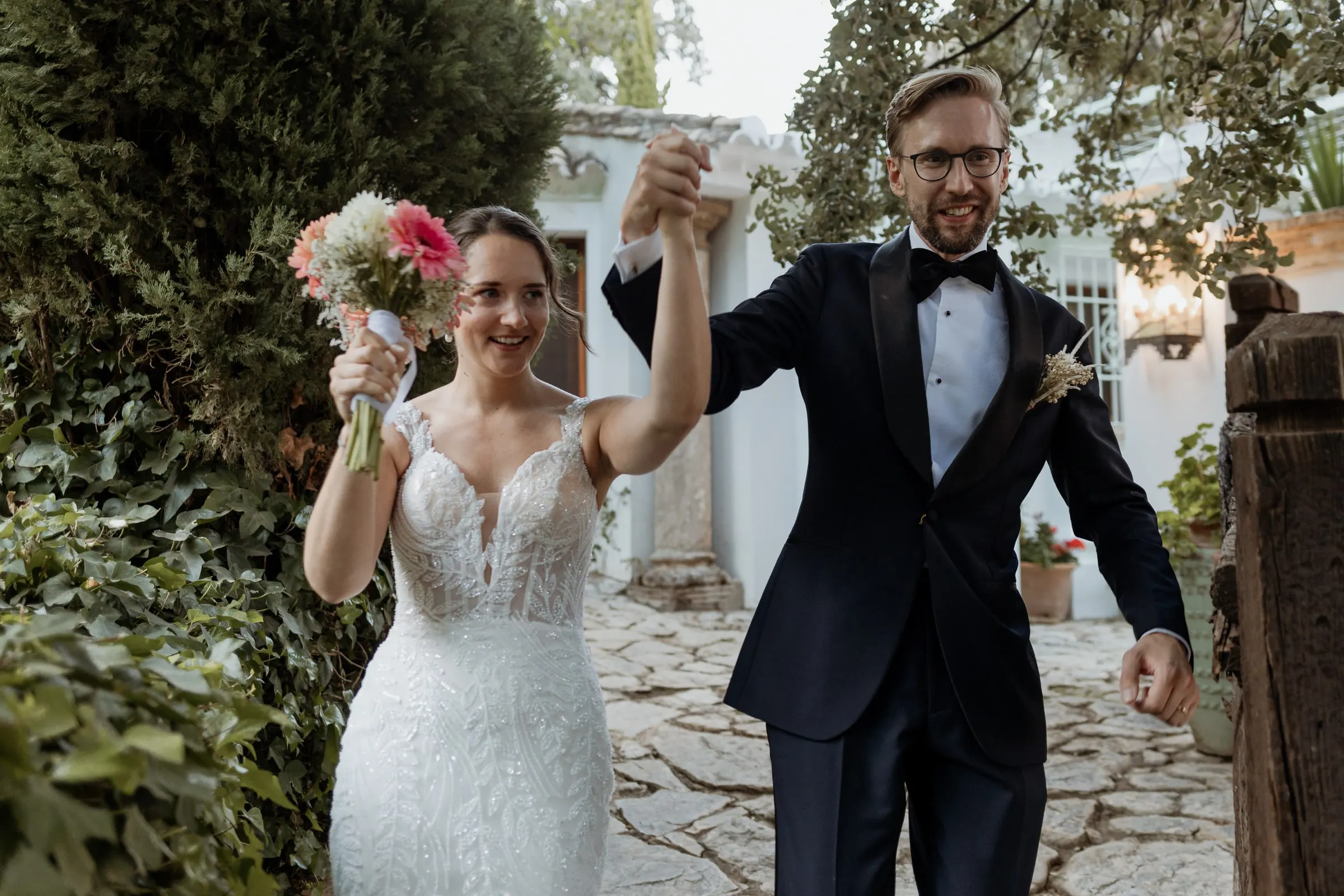 Bride and groom raising their arms as they arrive at the reception