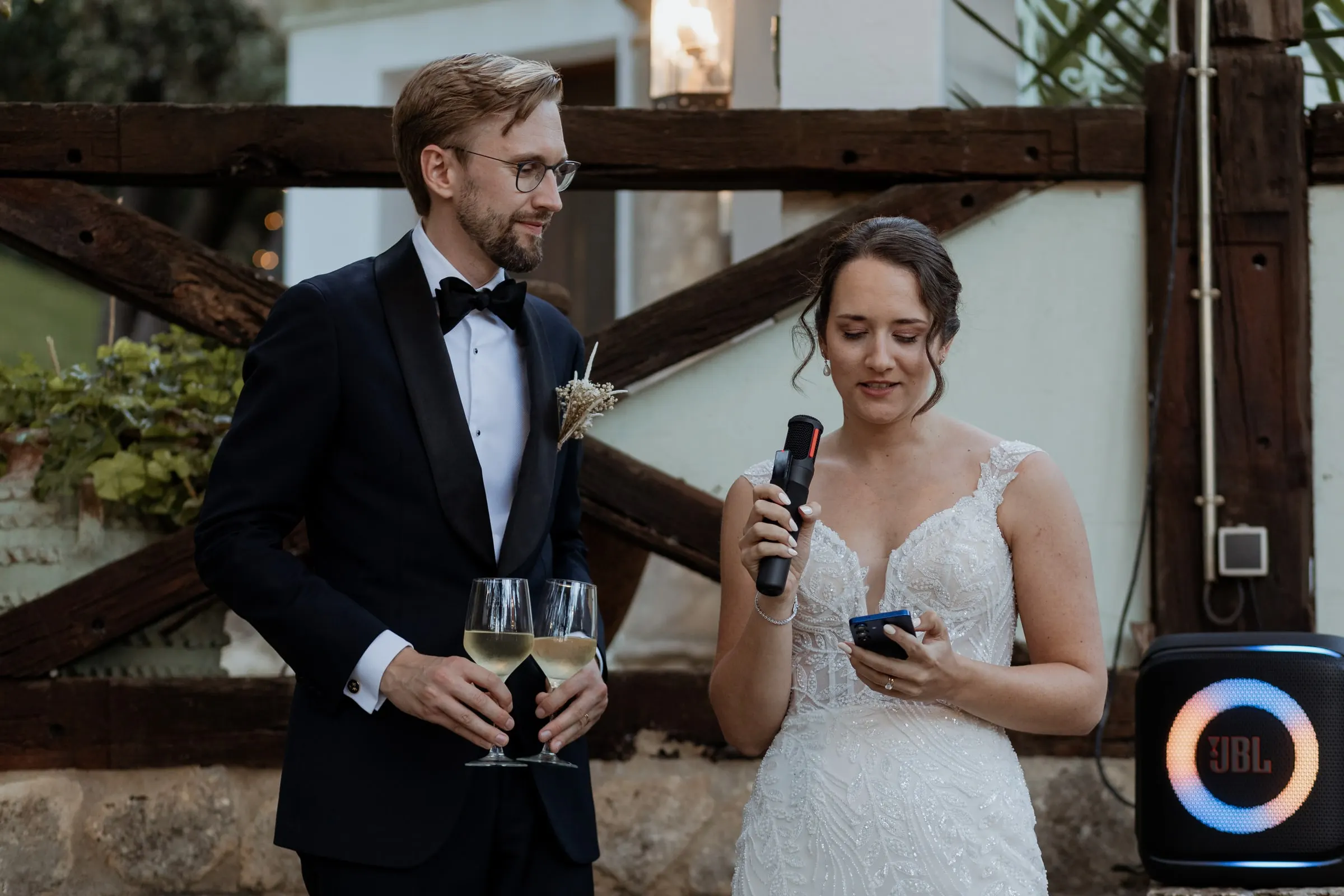 Groom giving a speech with the microphone while the bride listens