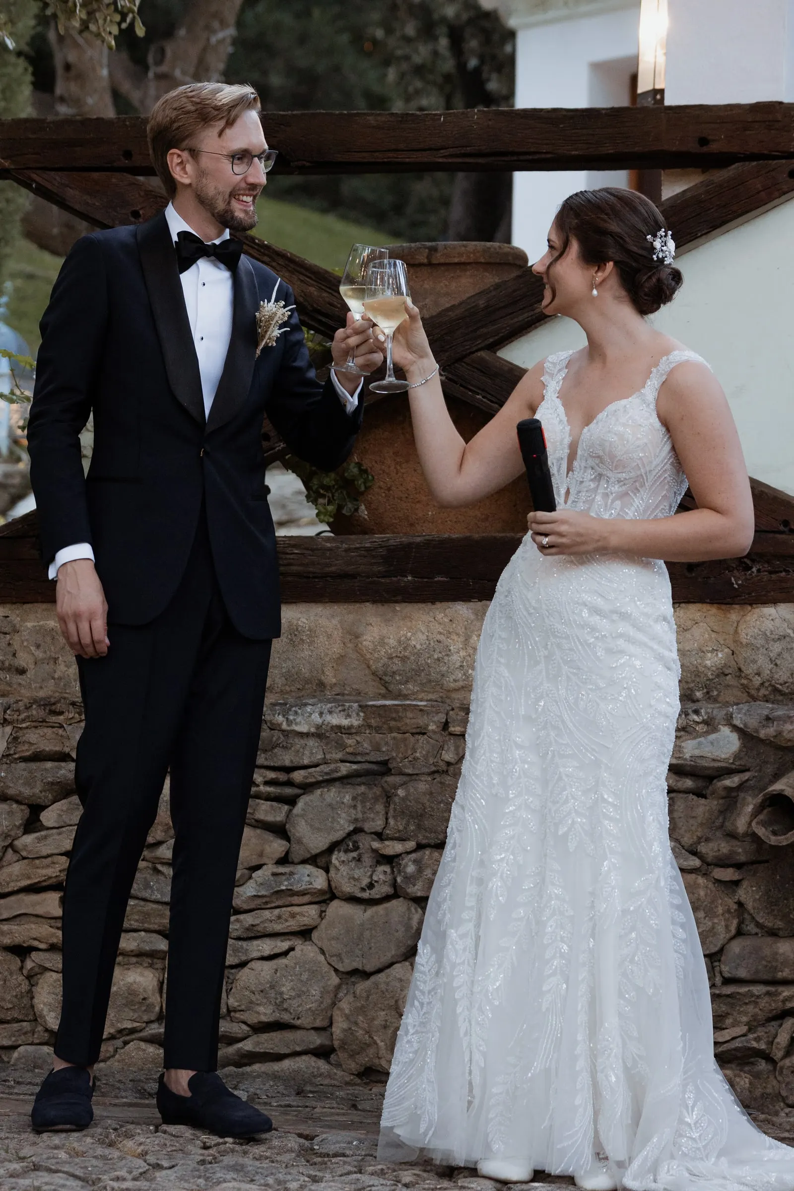 Couple clinking glasses after their speech against an old stone wall