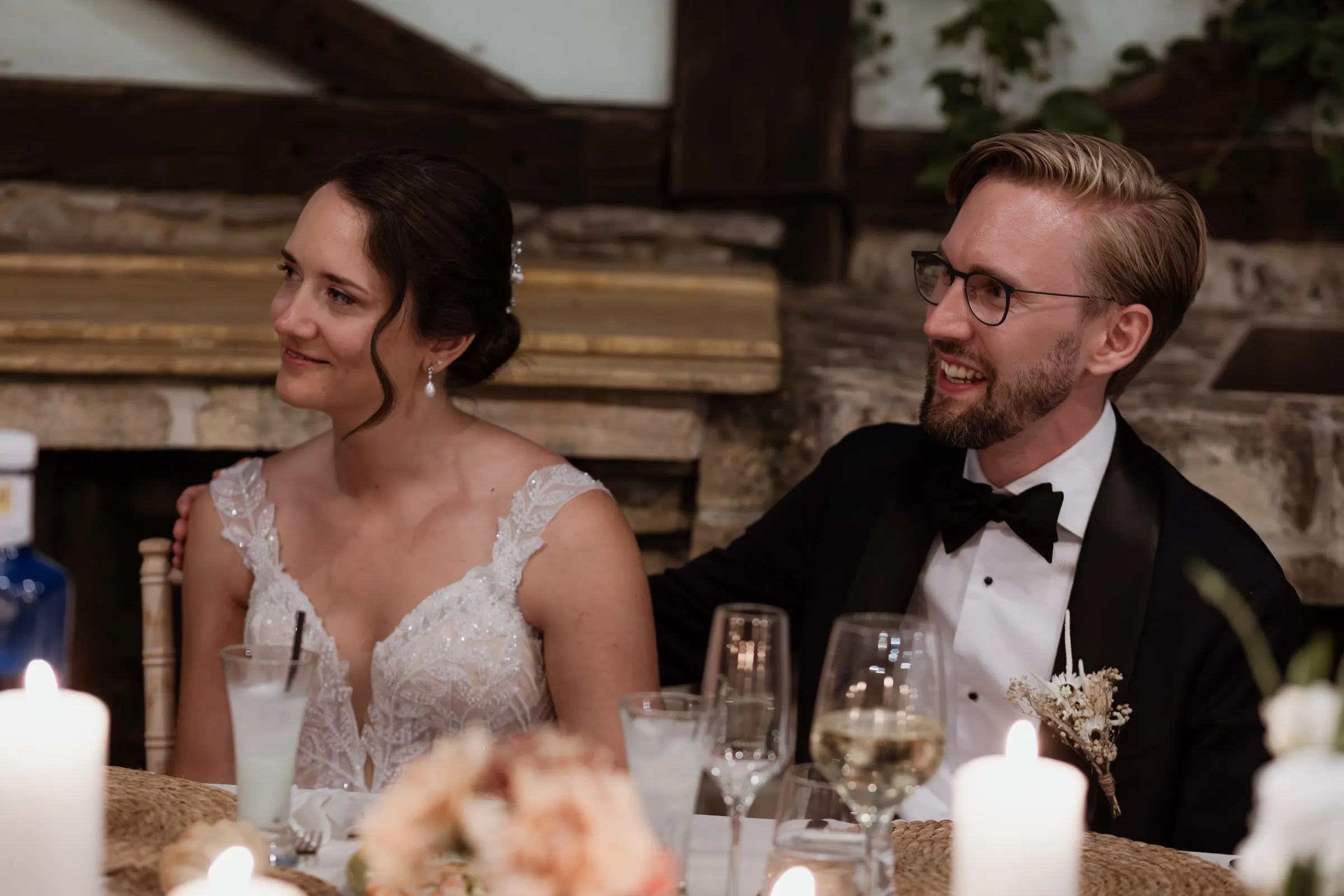 Bride and groom laughing together at their candlelit table