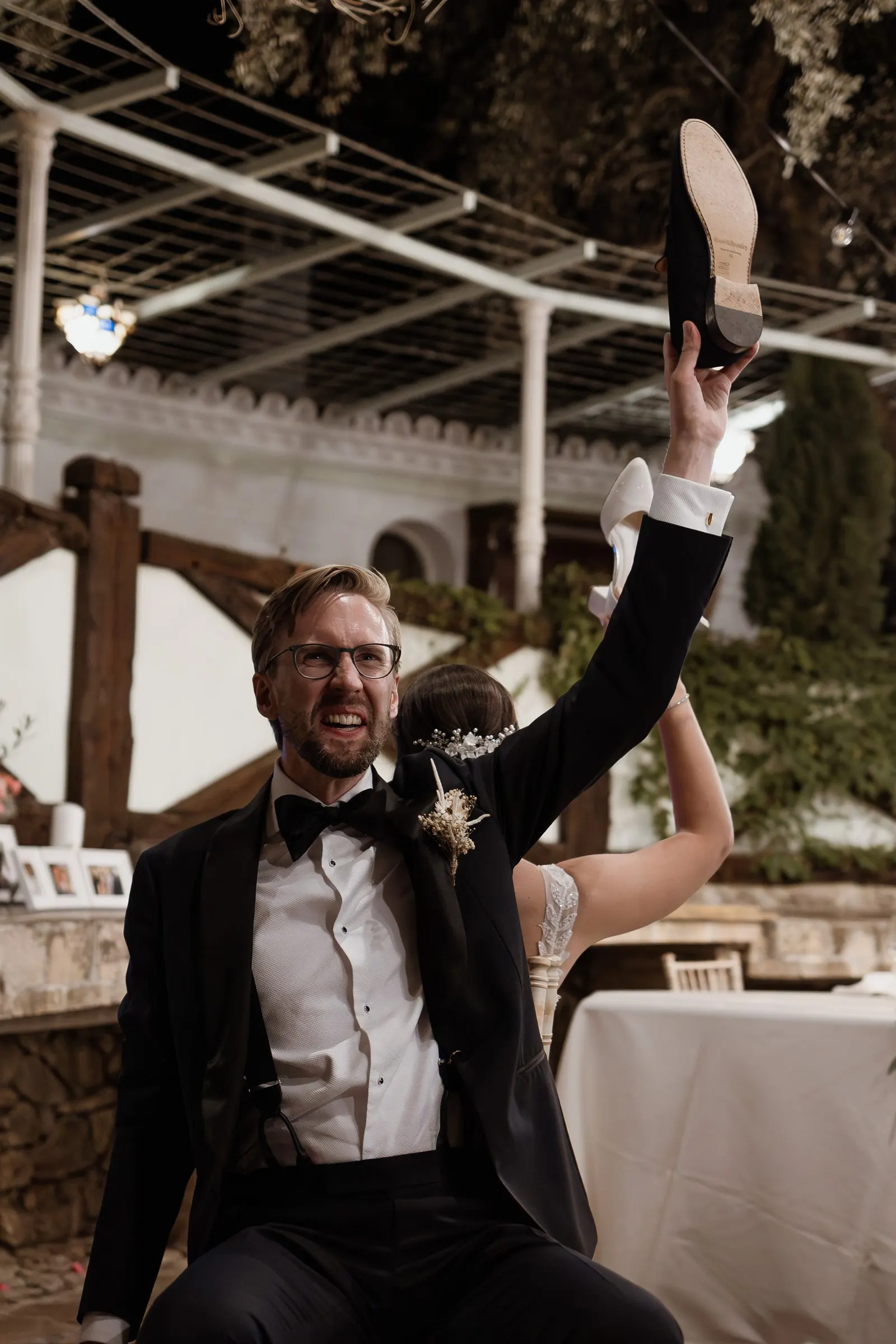 Groom holding up a shoe during the shoe game at dinner