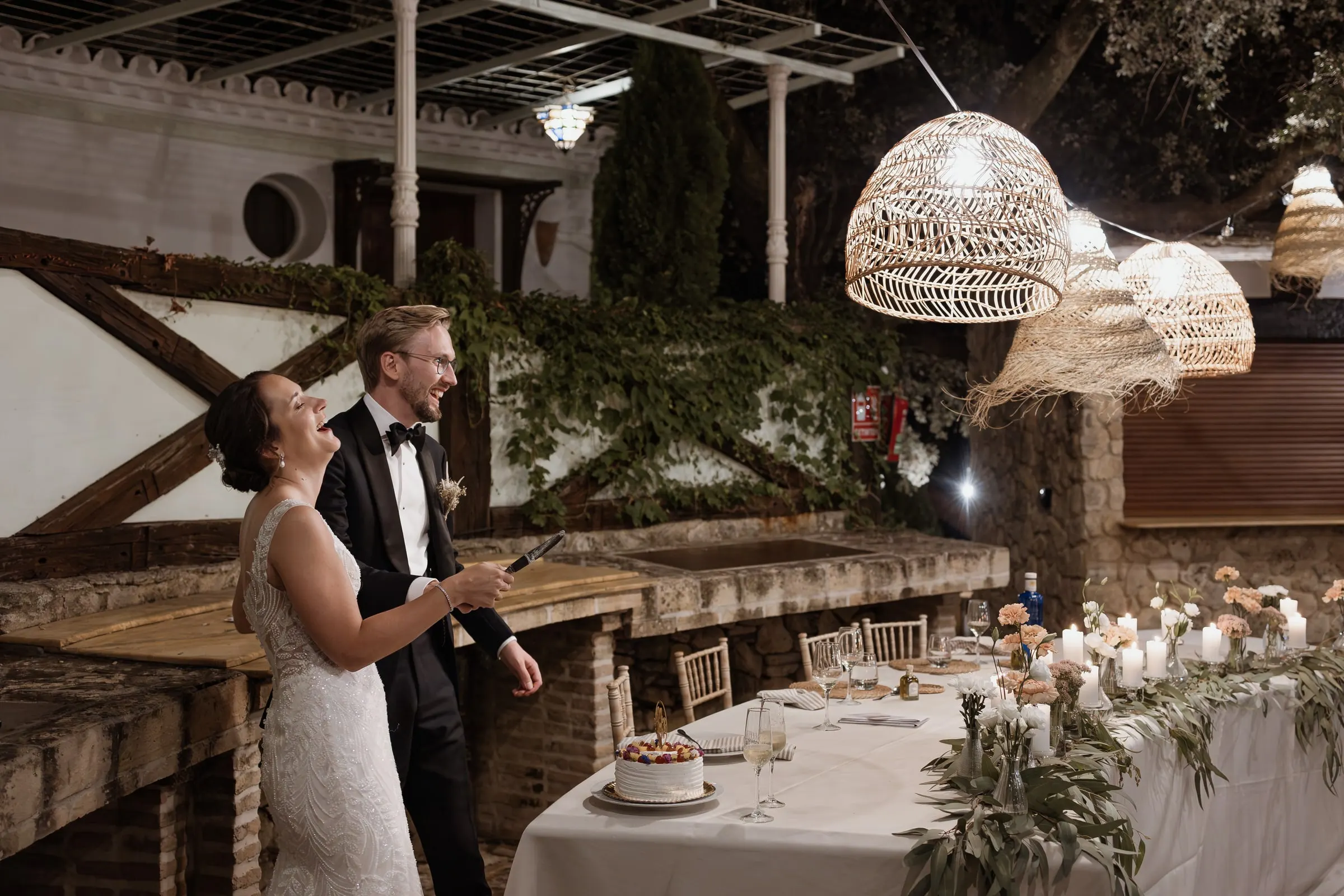 Bride and groom at the cake table under rattan lamps in Ronda