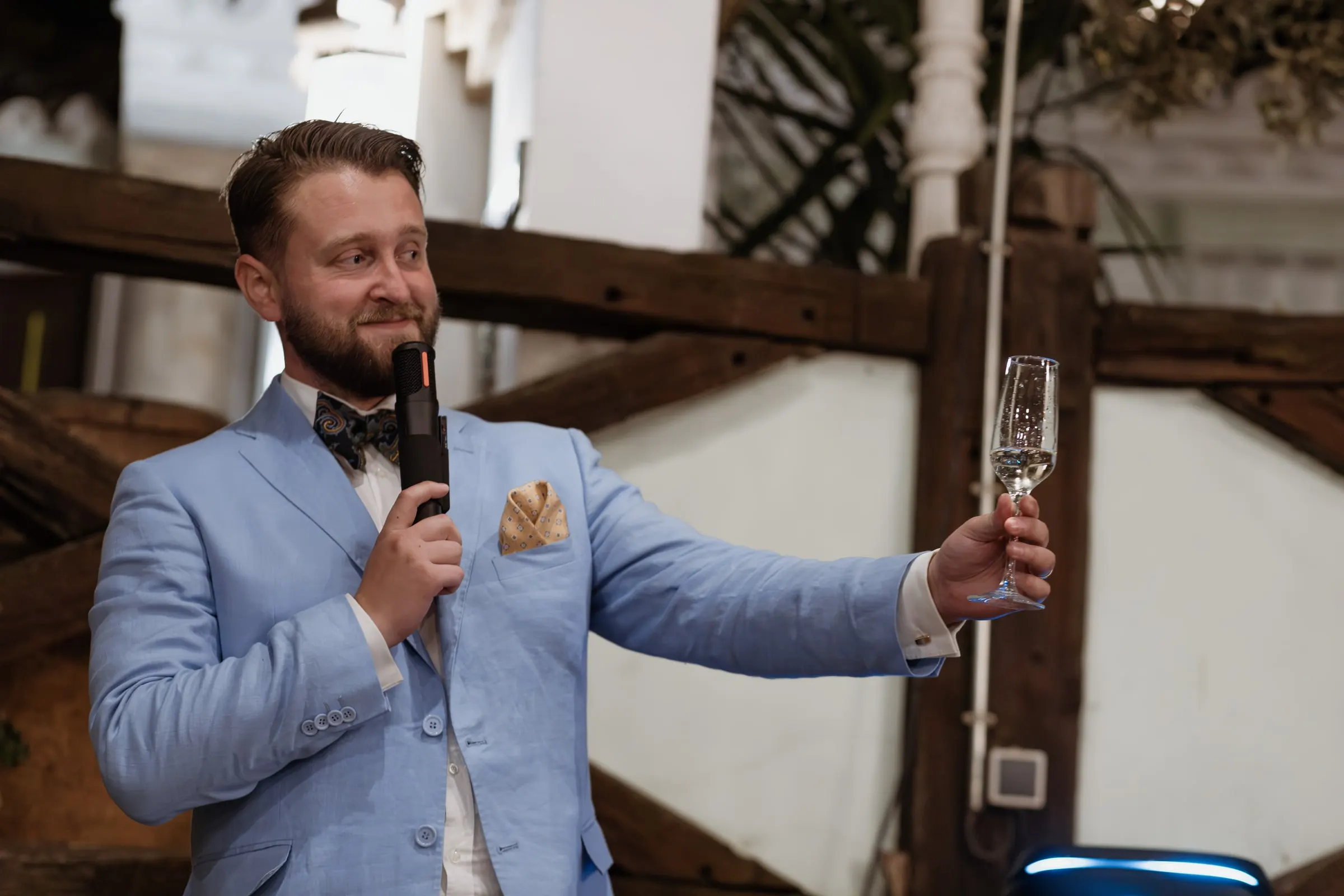 Best man in a light blue jacket raising his glass during his speech