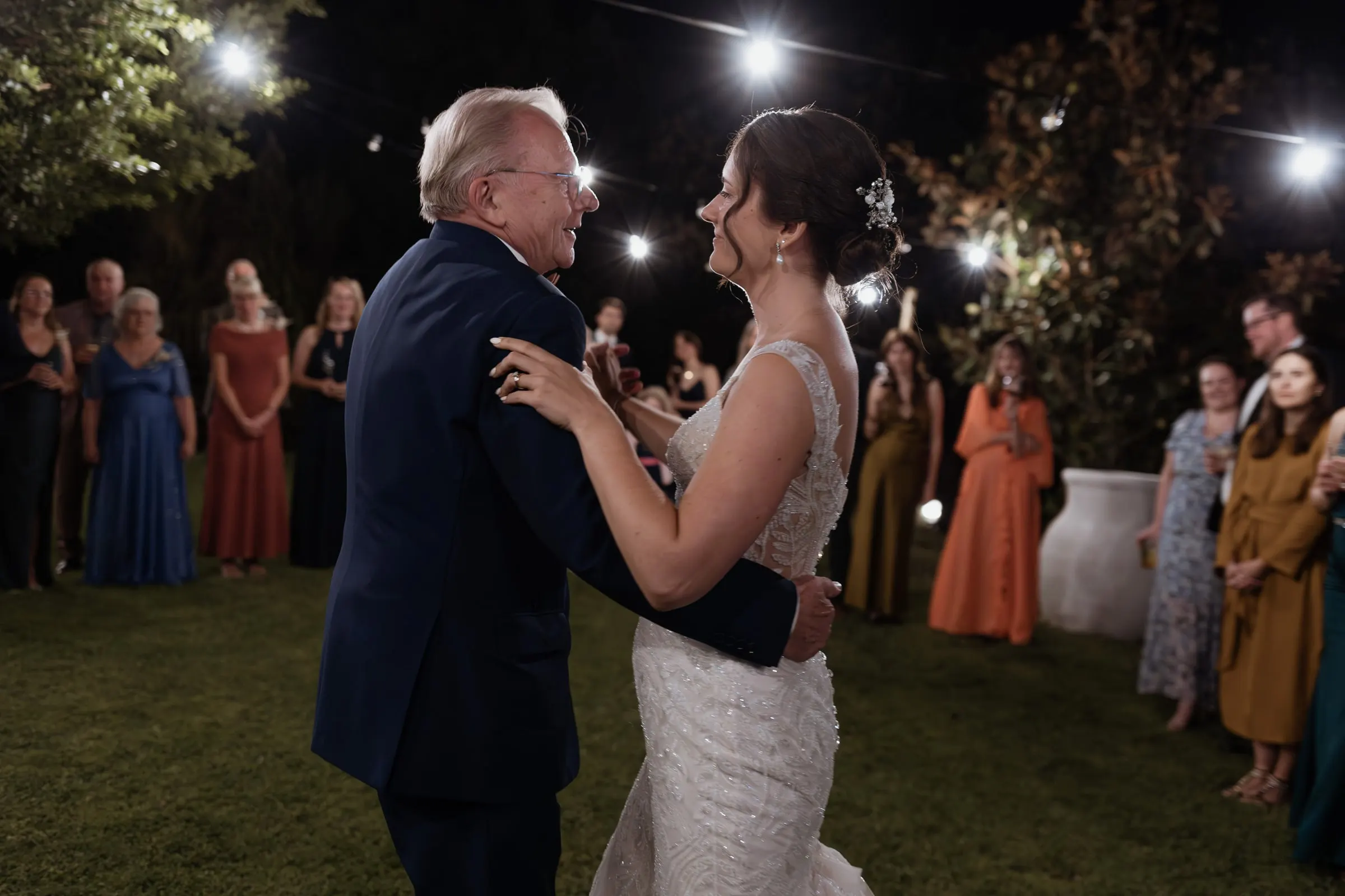 Bride dancing with an older guest in a navy suit