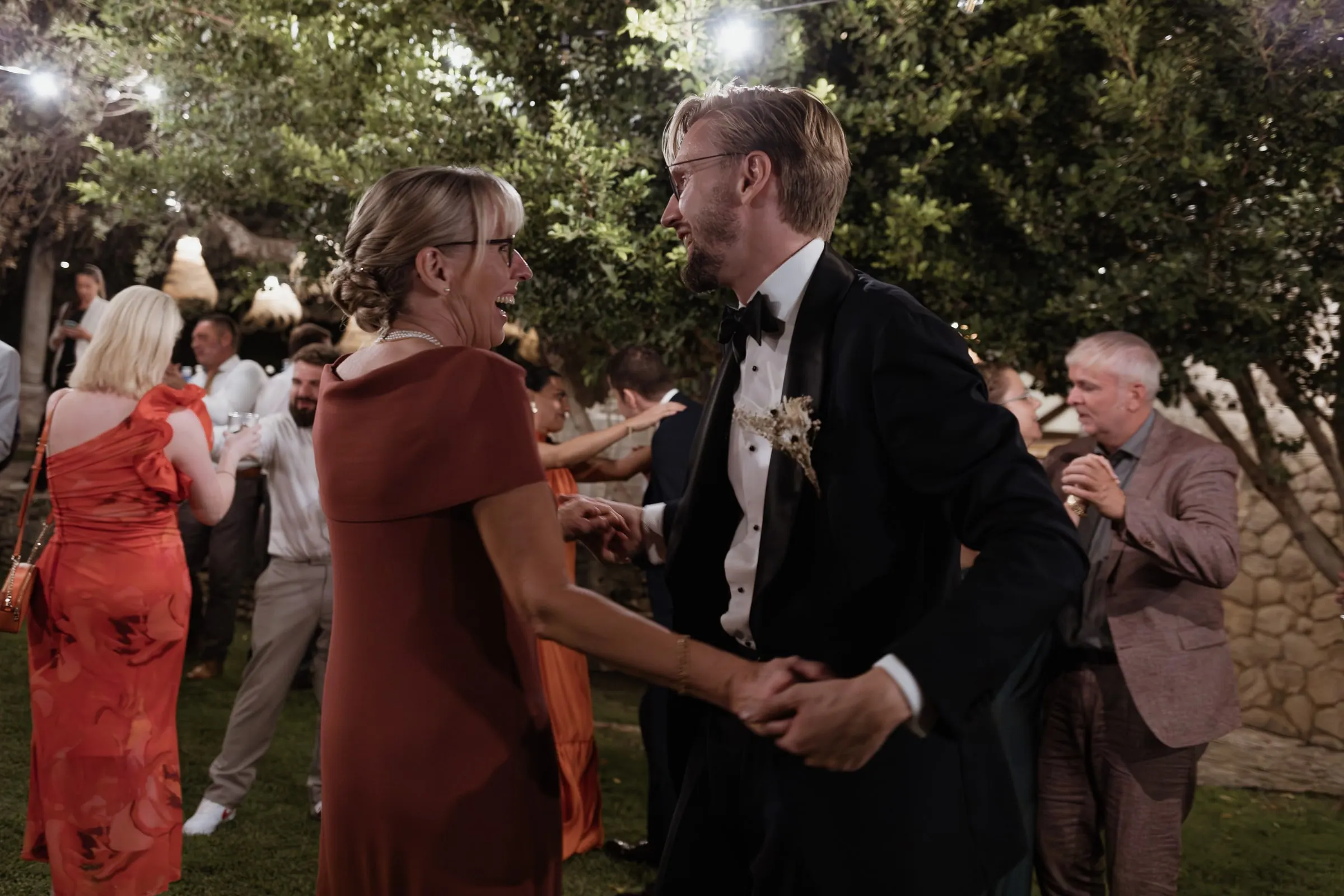 Groom dancing with a guest in a rust-coloured dress