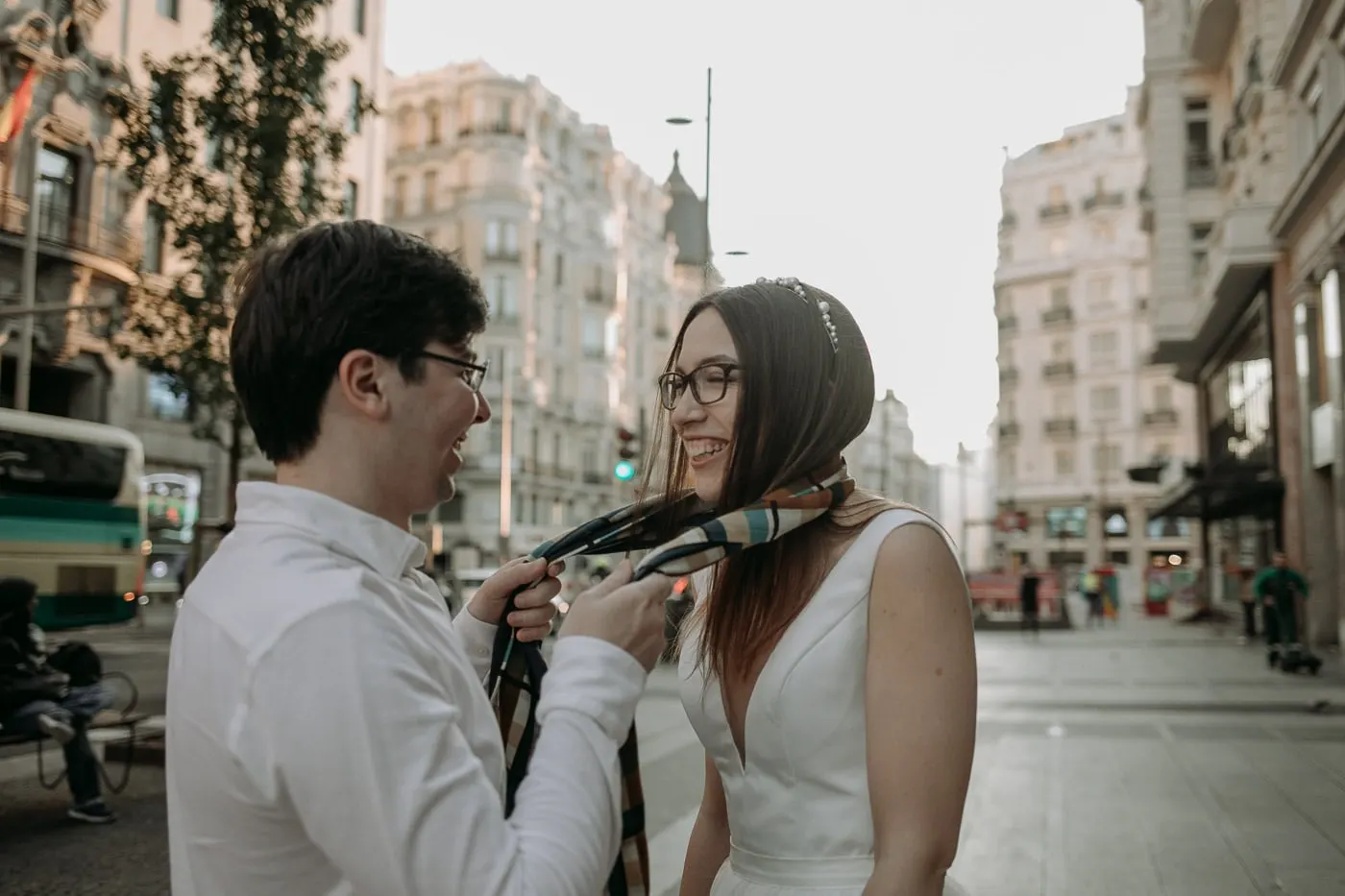 Groom tying a striped scarf around the bride's neck on Gran Vía, Madrid