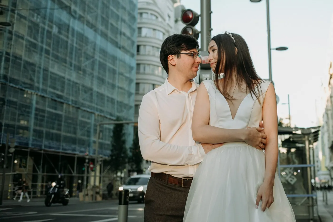 Couple embracing at a street corner with traffic lights behind