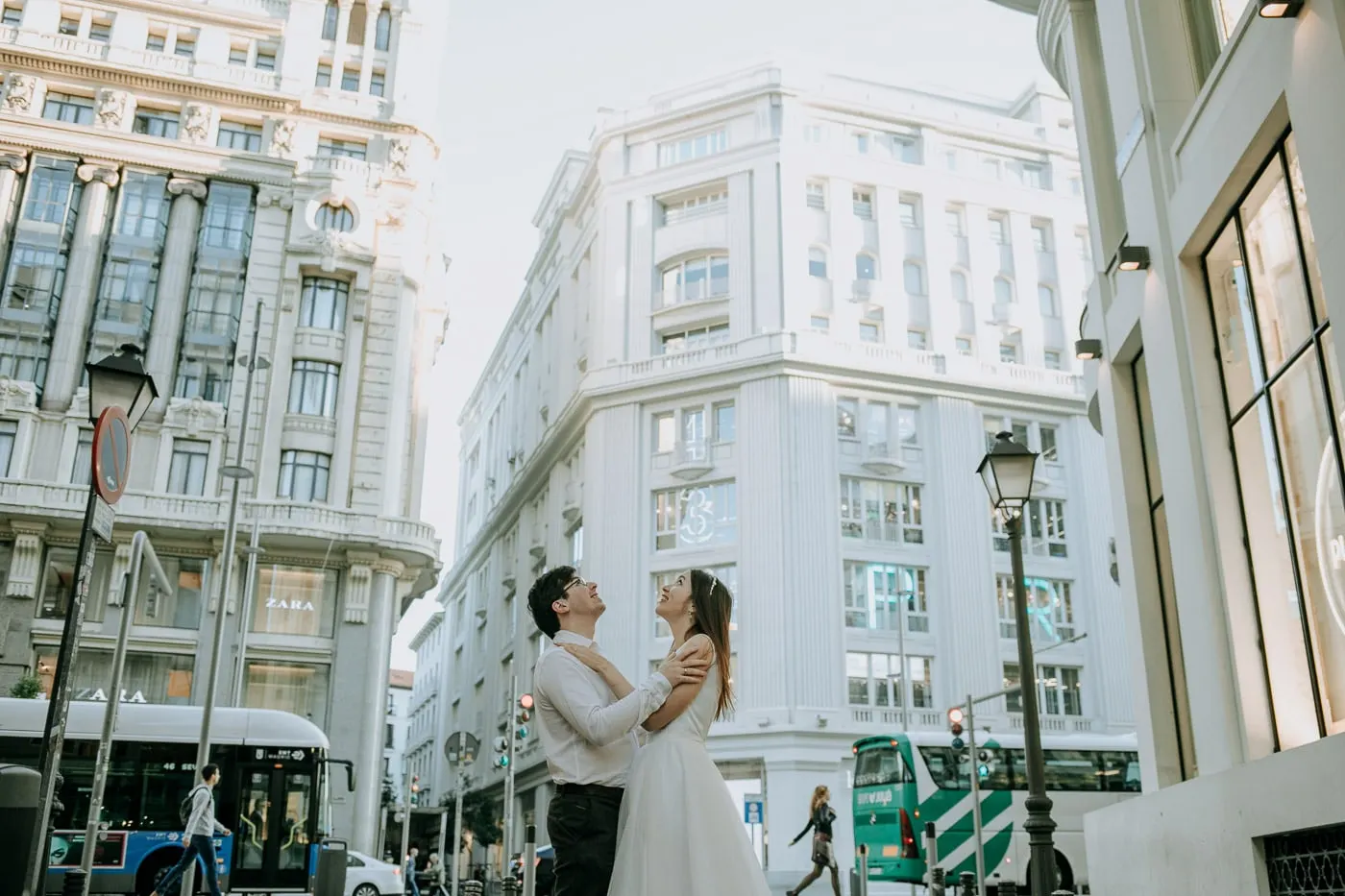 Couple embracing in front of a white corner building on Gran Vía
