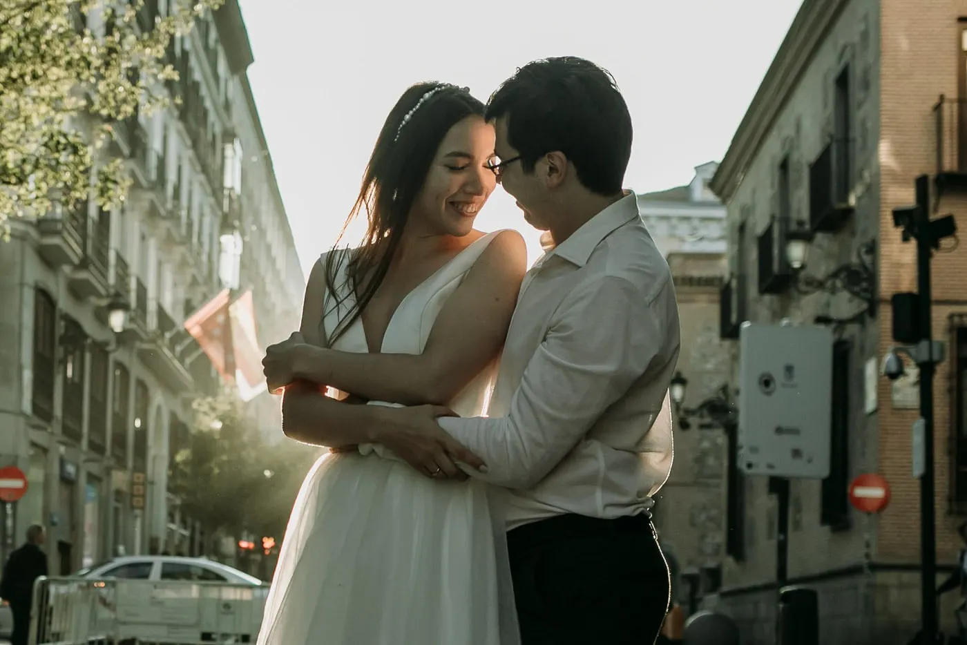 Bride and groom hugging in a narrow Madrid street, backlit