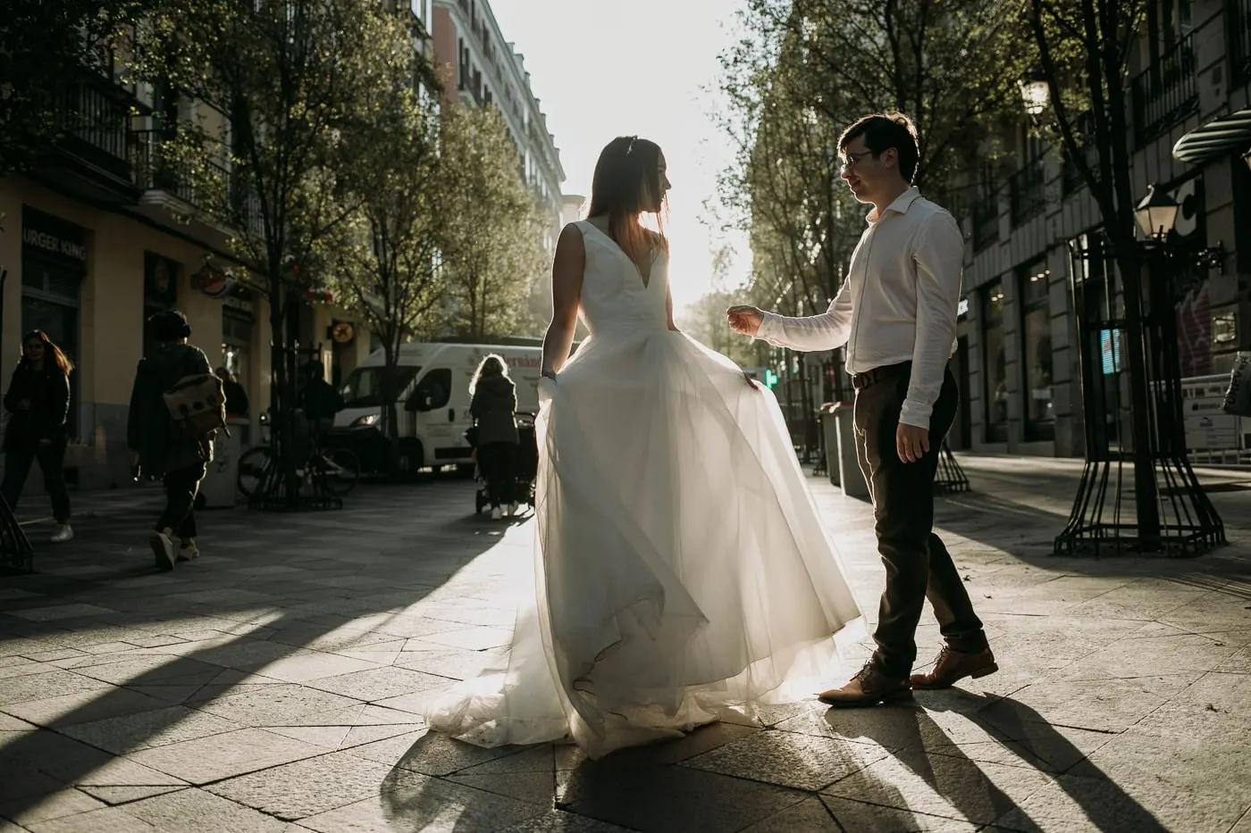 Groom twirling the bride on a sunlit pavement in central Madrid