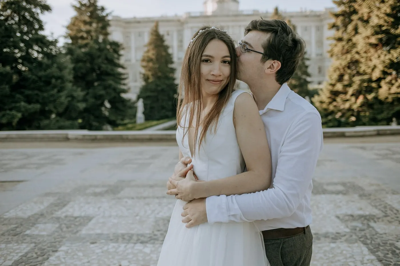 Groom kissing the bride's temple near the Royal Palace, Madrid