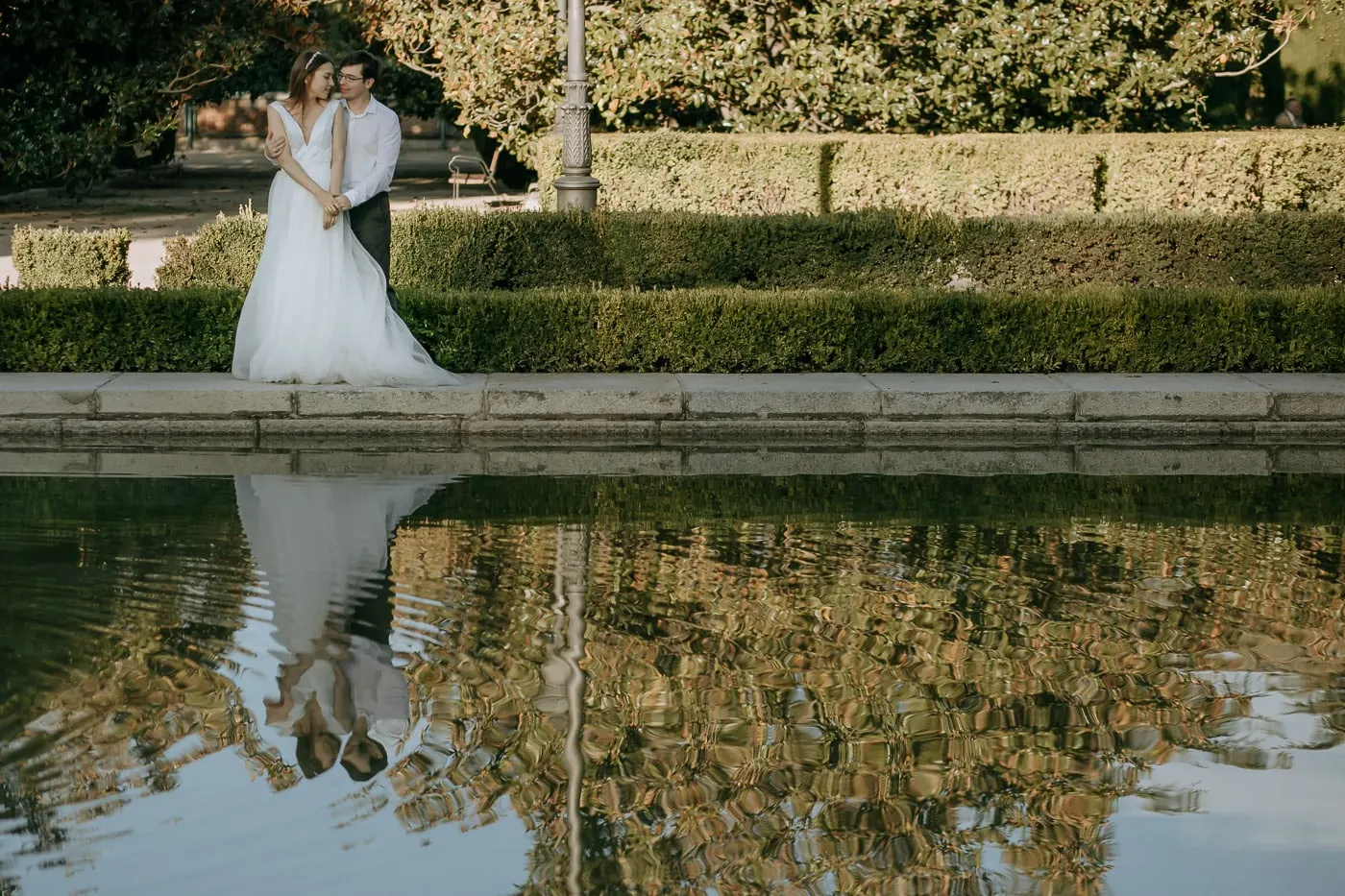 Couple reflected in the still water of a garden pond, Madrid