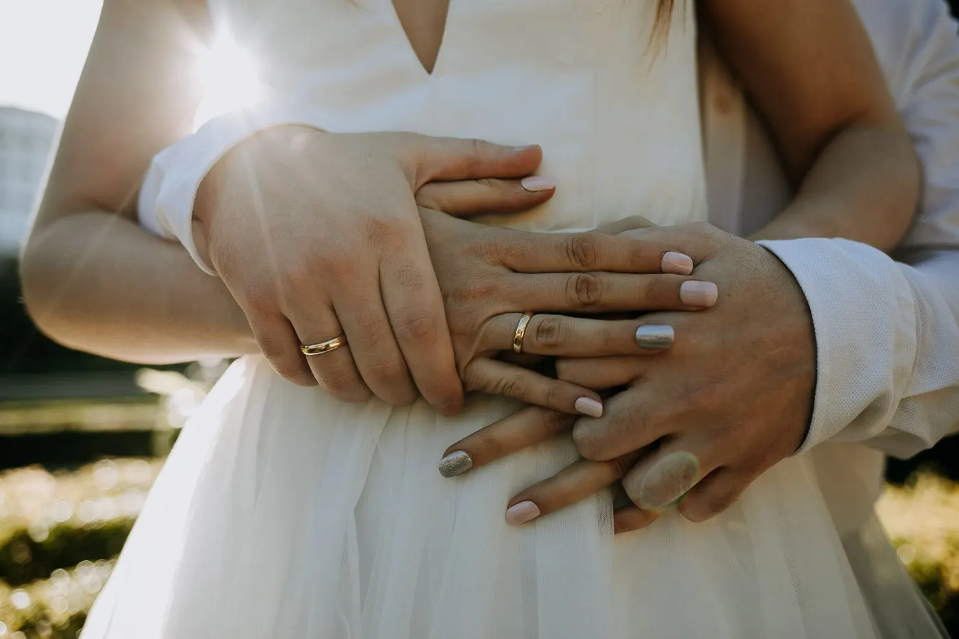 Close-up of their hands and wedding rings on the tulle dress