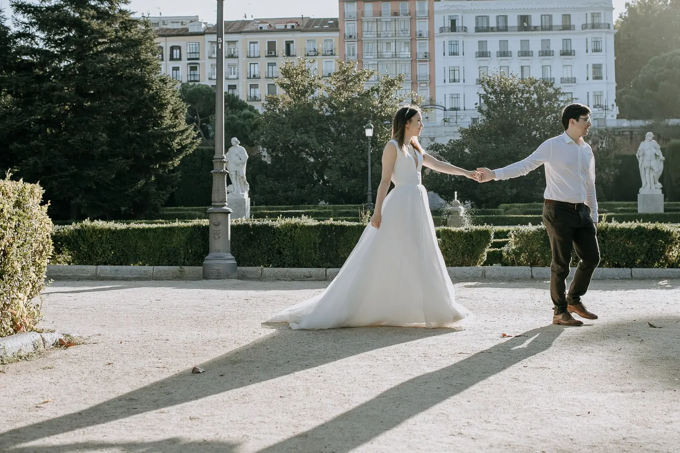 Couple holding hands among the statues and hedges near the Royal Palace
