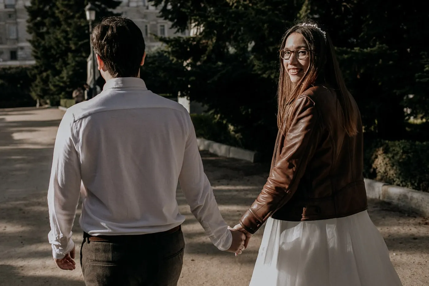 Bride in a leather jacket looking back as she leads the groom