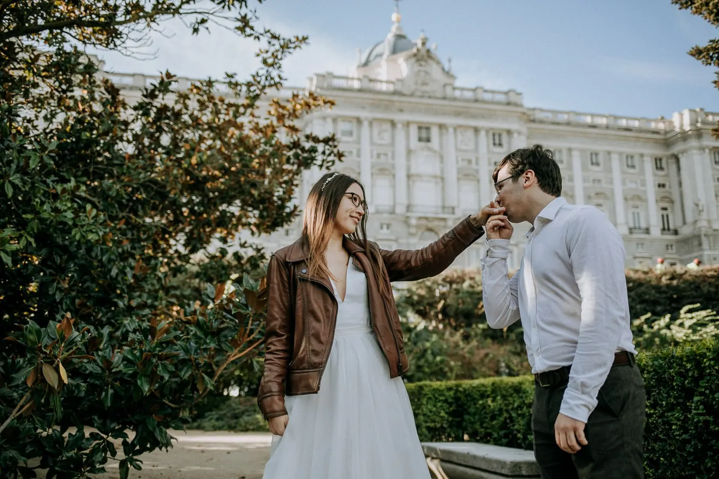 Groom kissing the bride's hand with the Royal Palace behind, Madrid