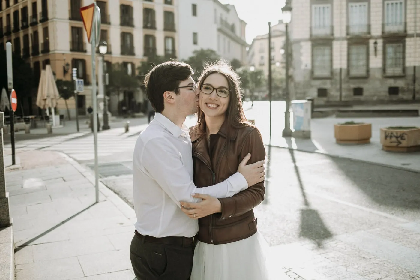 Groom kissing the bride's cheek on a sunny street corner