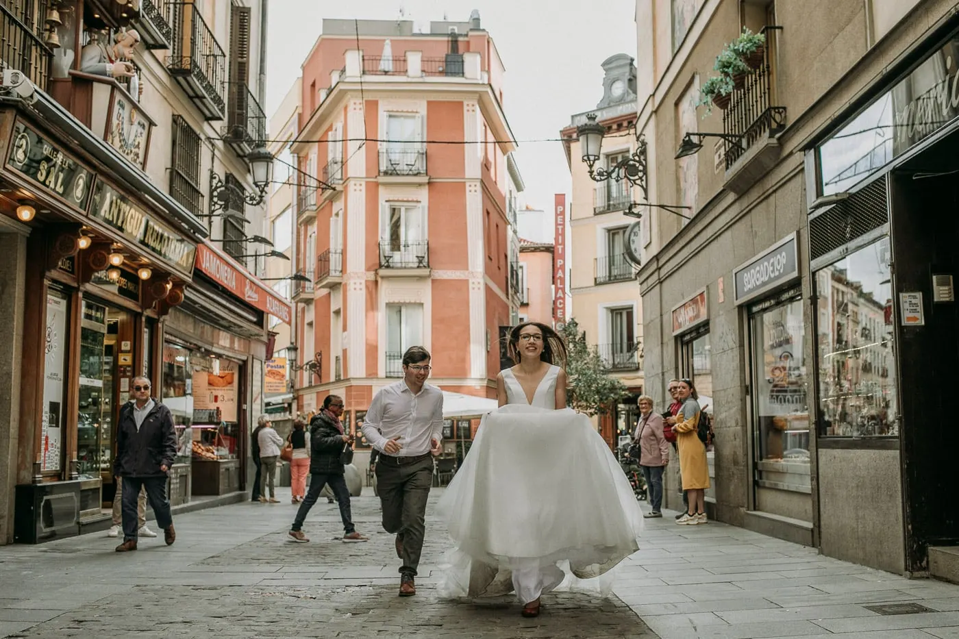 Couple running down a busy shopping street in central Madrid