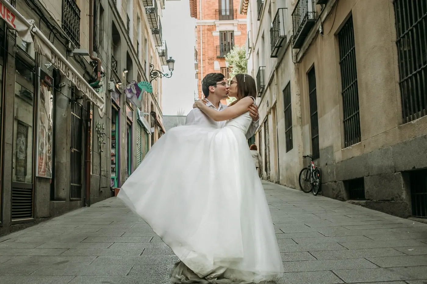 Groom lifting the bride for a kiss in a narrow old street