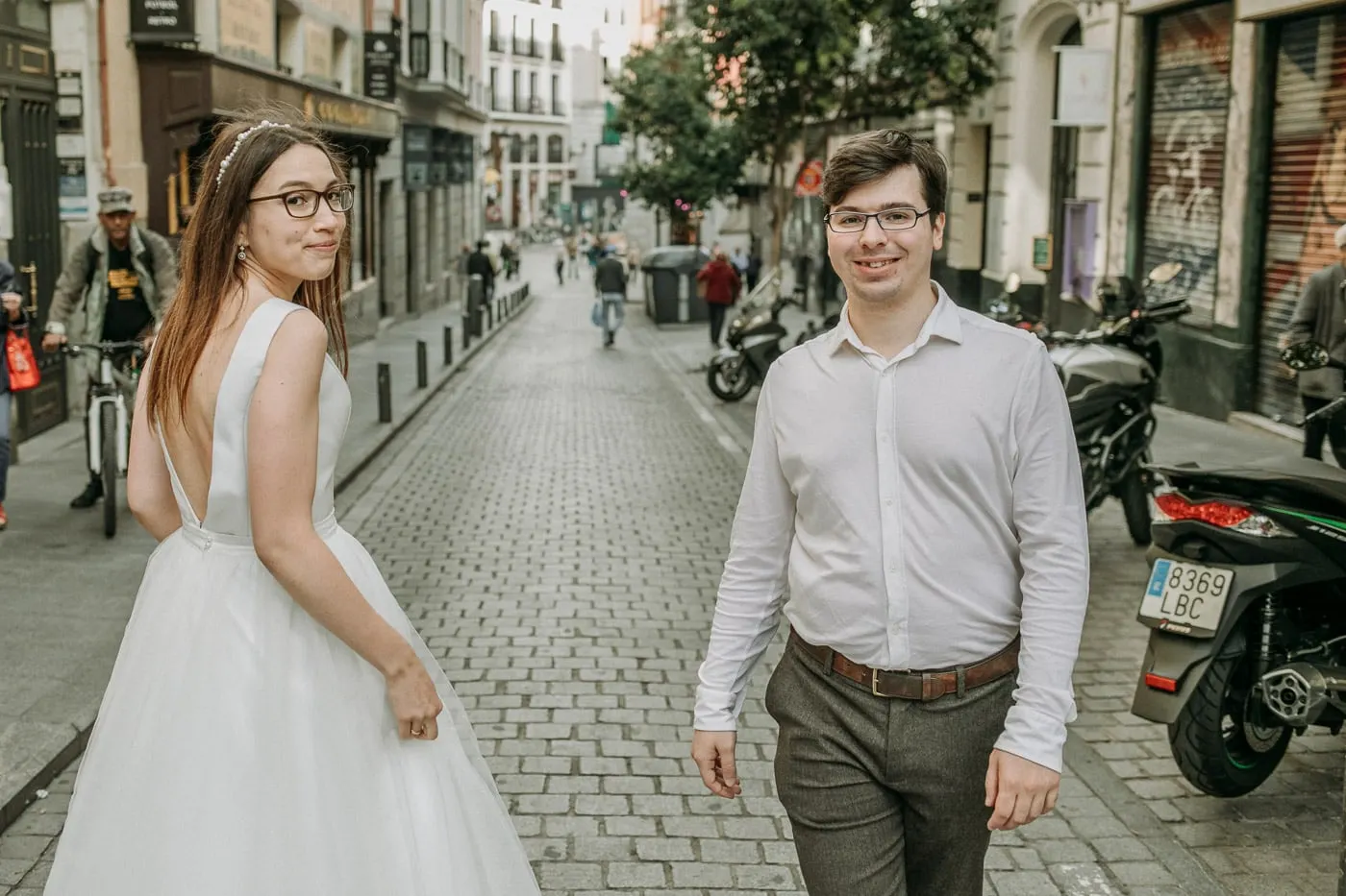Bride glancing back at the groom on a cobbled street, Madrid