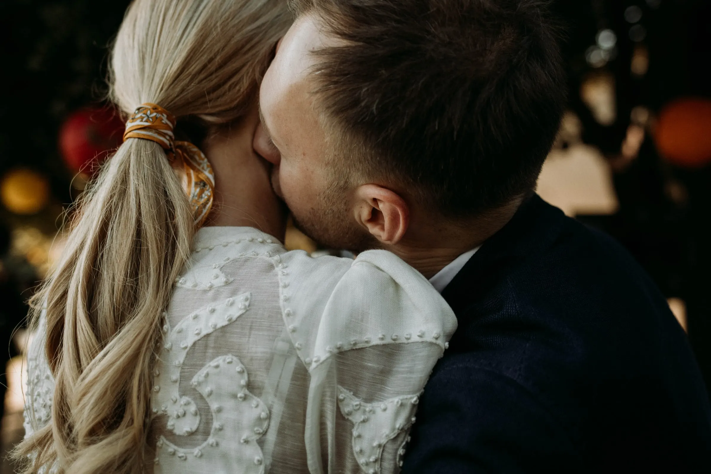 The groom kissing the bride's cheek, her ponytail tied with a gold band, at a masia in Girona