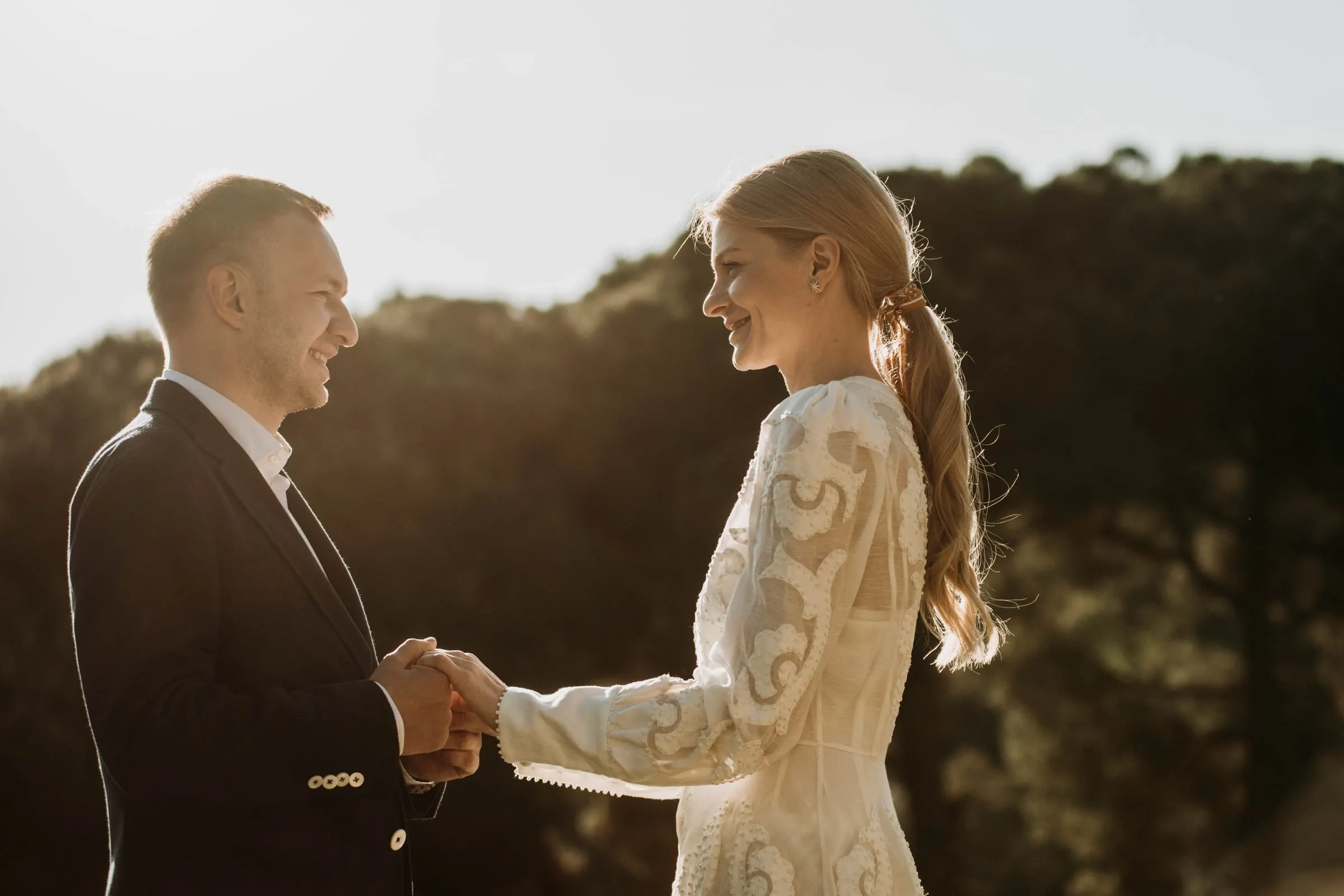 Bride and groom holding hands and smiling in warm backlight on the terrace of a masia in Girona