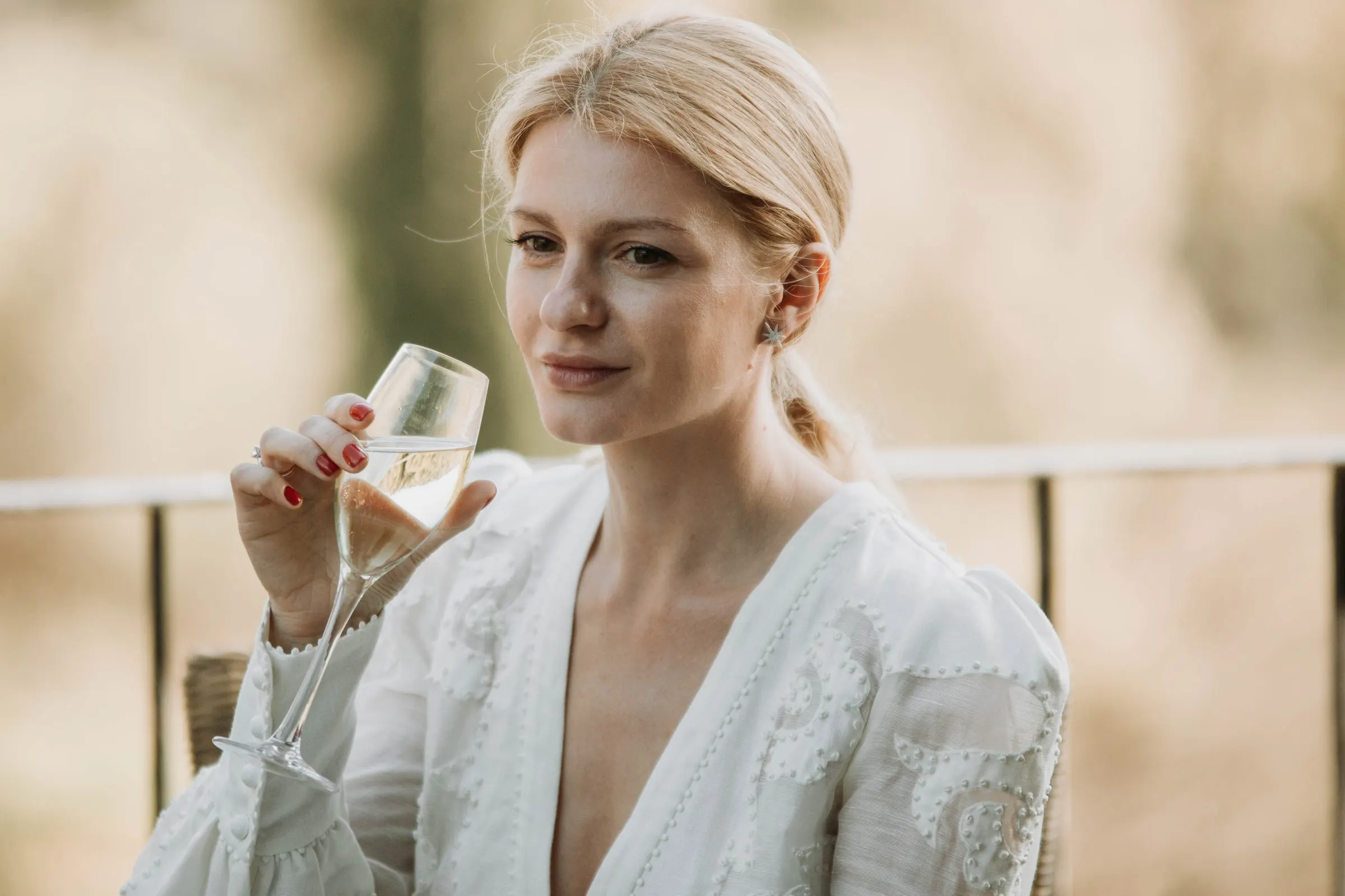 The bride holding a glass of cava and gazing to one side on the terrace of a masia in Girona