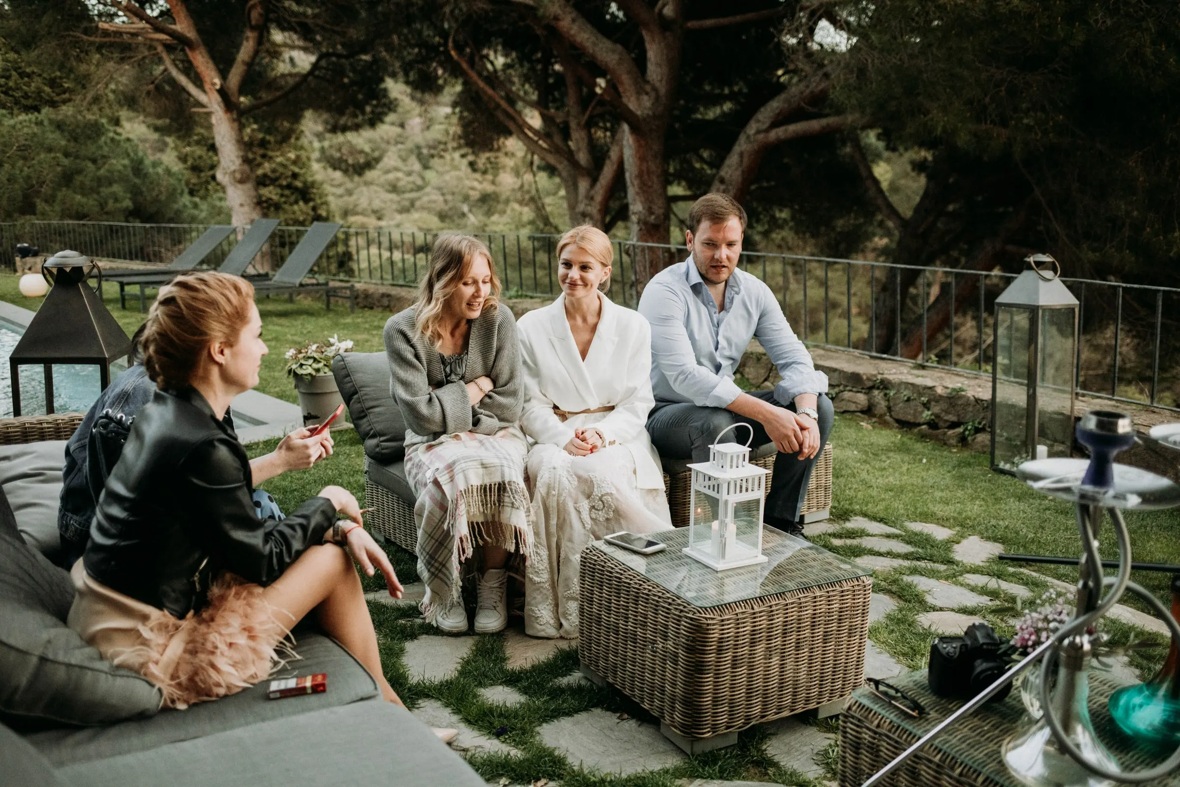 The bride and friends chatting on wicker sofas in the garden of a masia in Girona