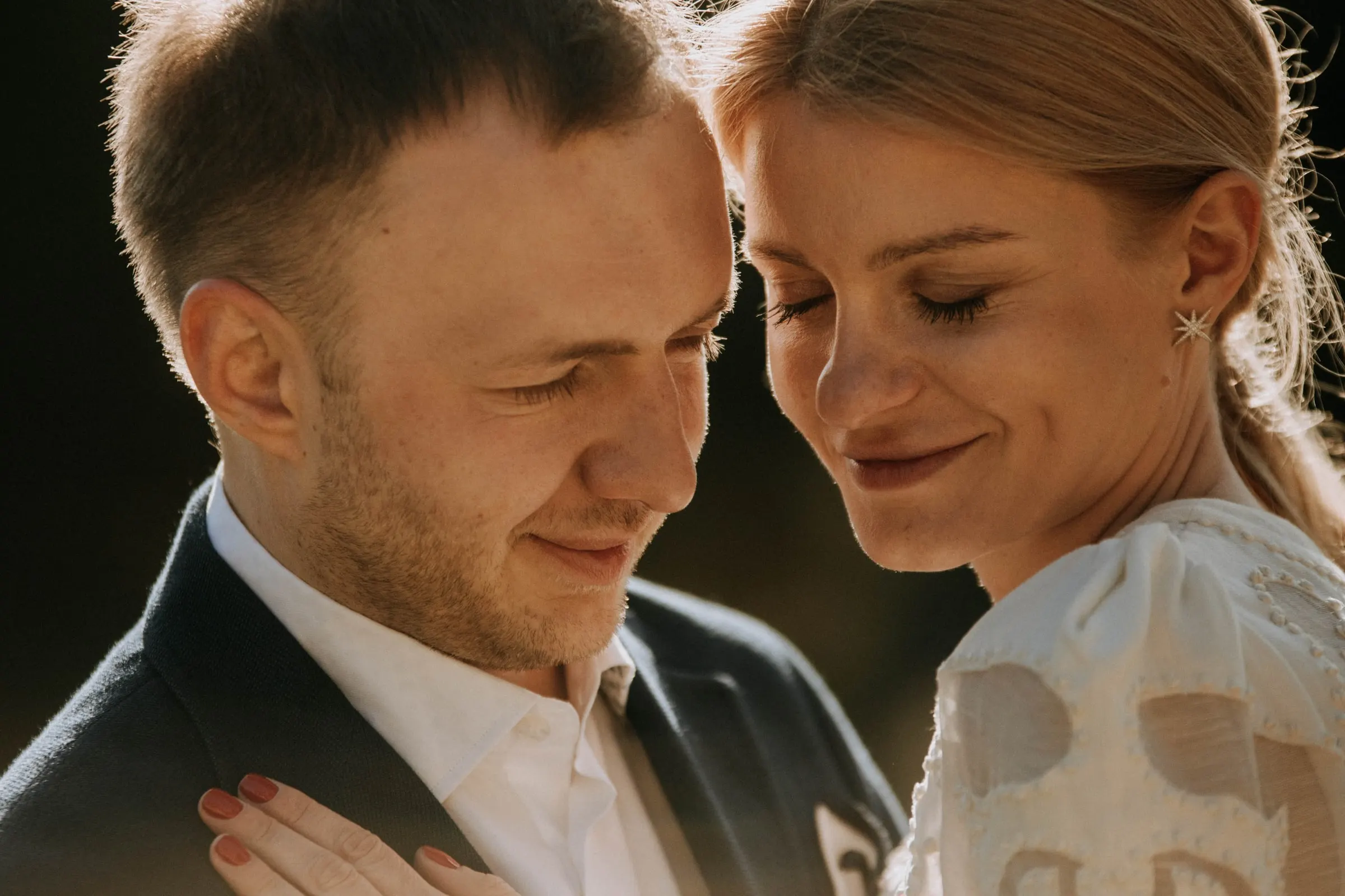 Close-up of the couple cheek to cheek with eyes closed in warm light at a masia in Girona