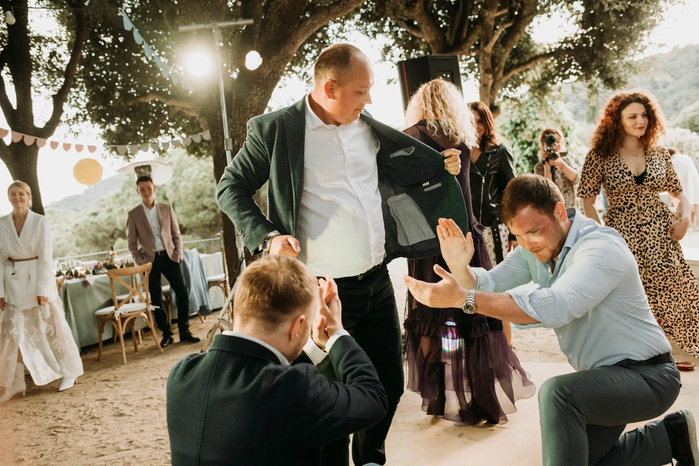Guests dancing and kneeling in a circle on the outdoor dance floor at a masia in Girona