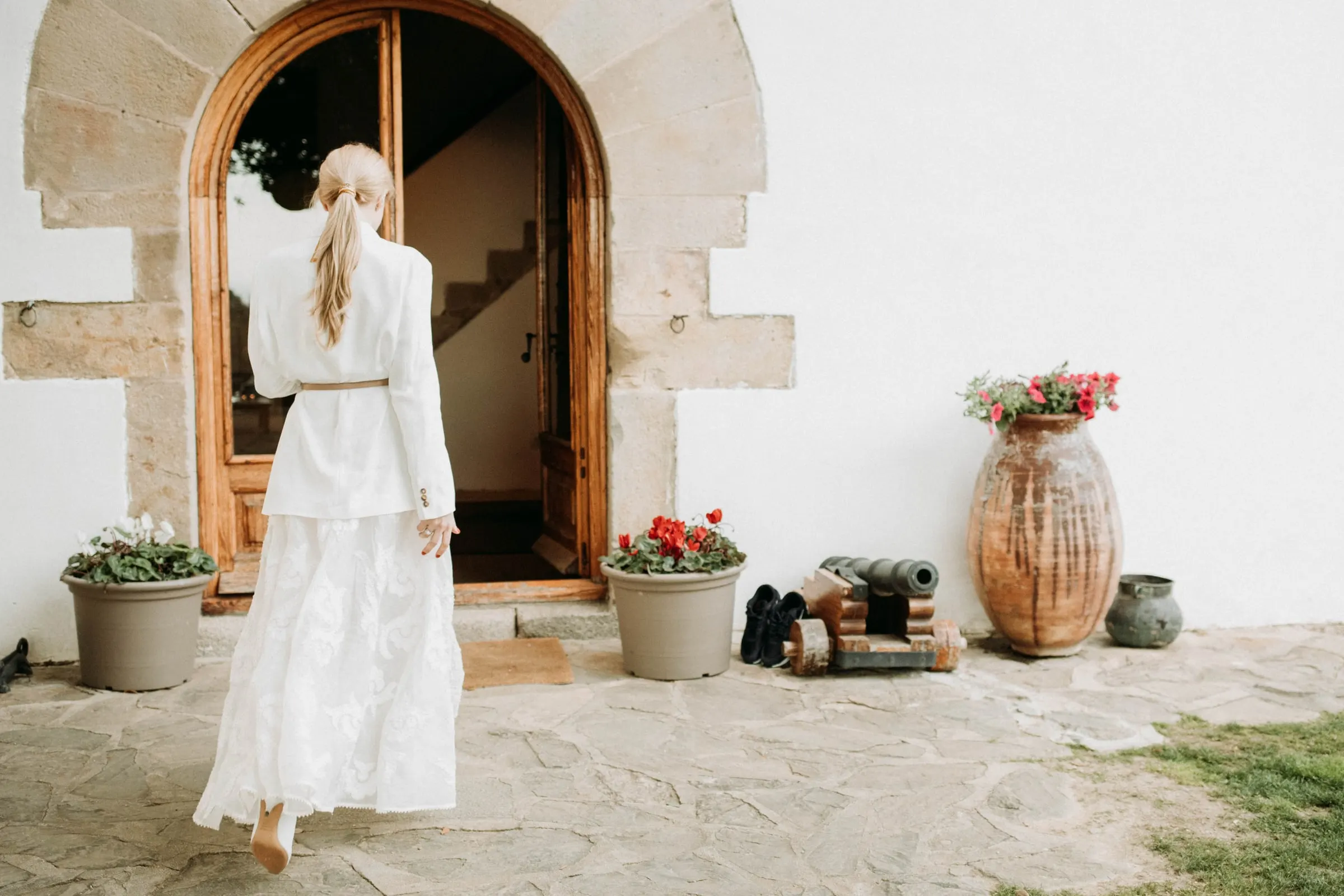 The bride seen from behind walking towards the arched stone doorway of a masia in Girona