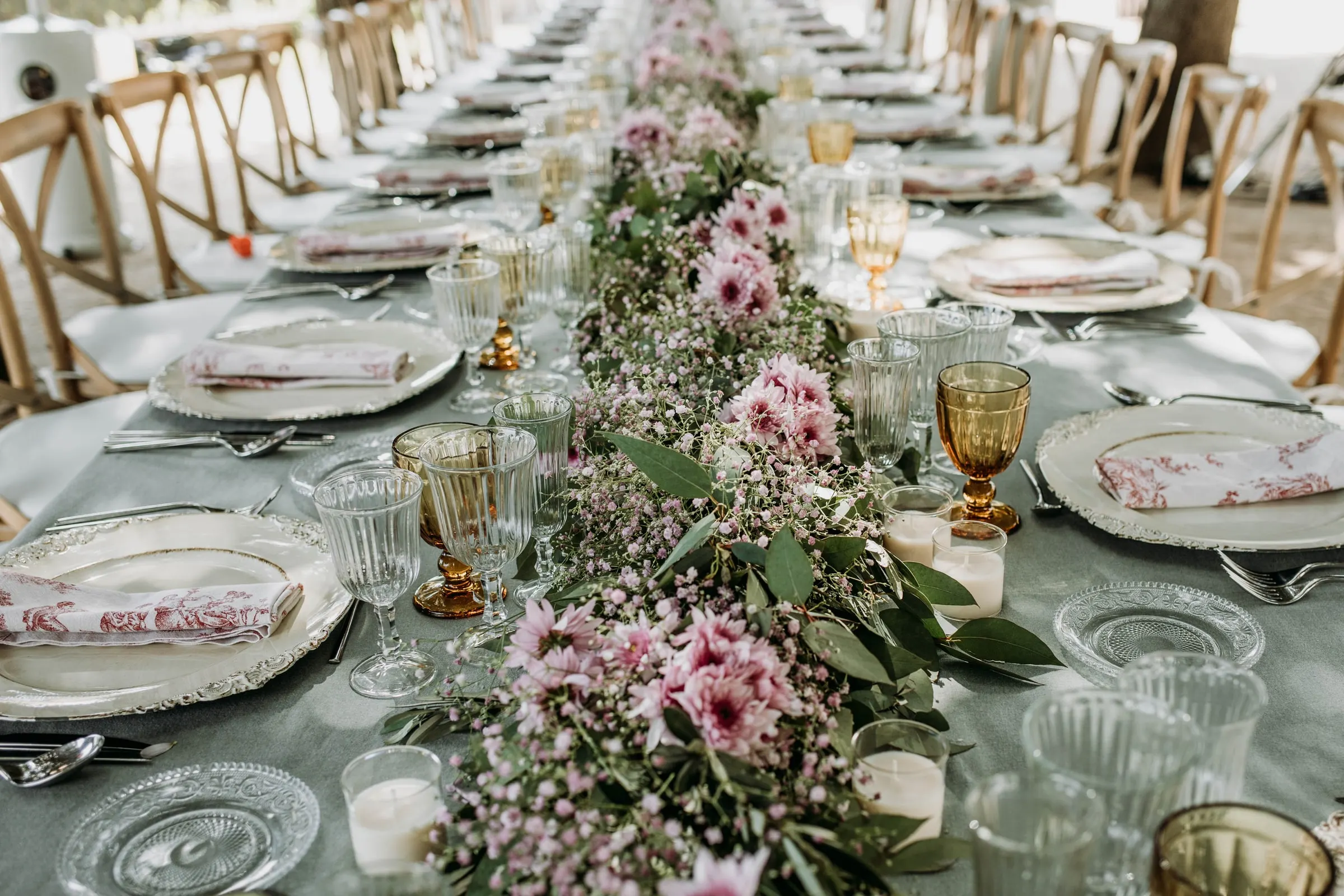 The long banquet table dressed with pink flowers and amber glasses at a masia in Girona