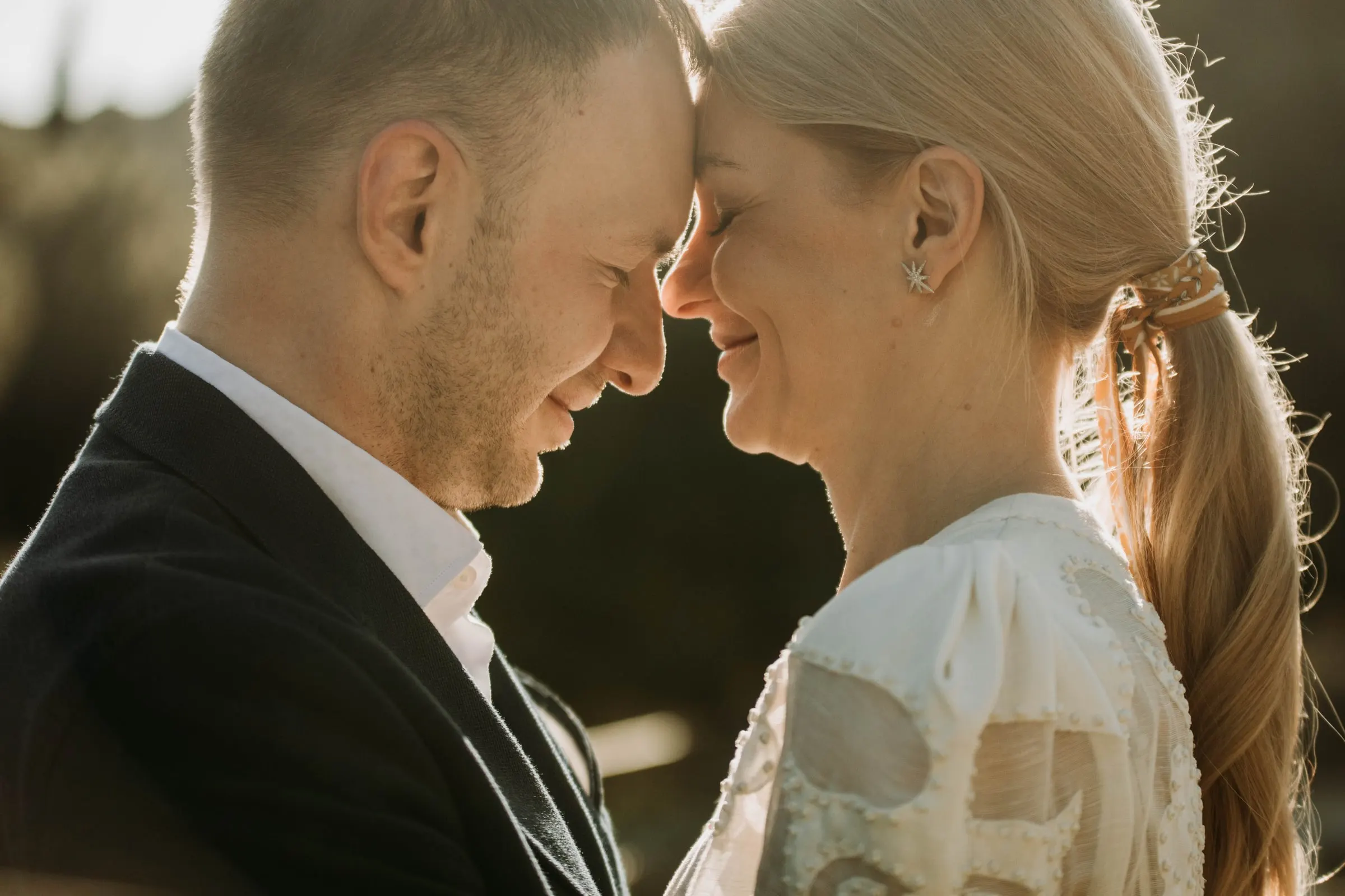 The couple forehead to forehead, eyes closed, in soft backlight at a masia in Girona