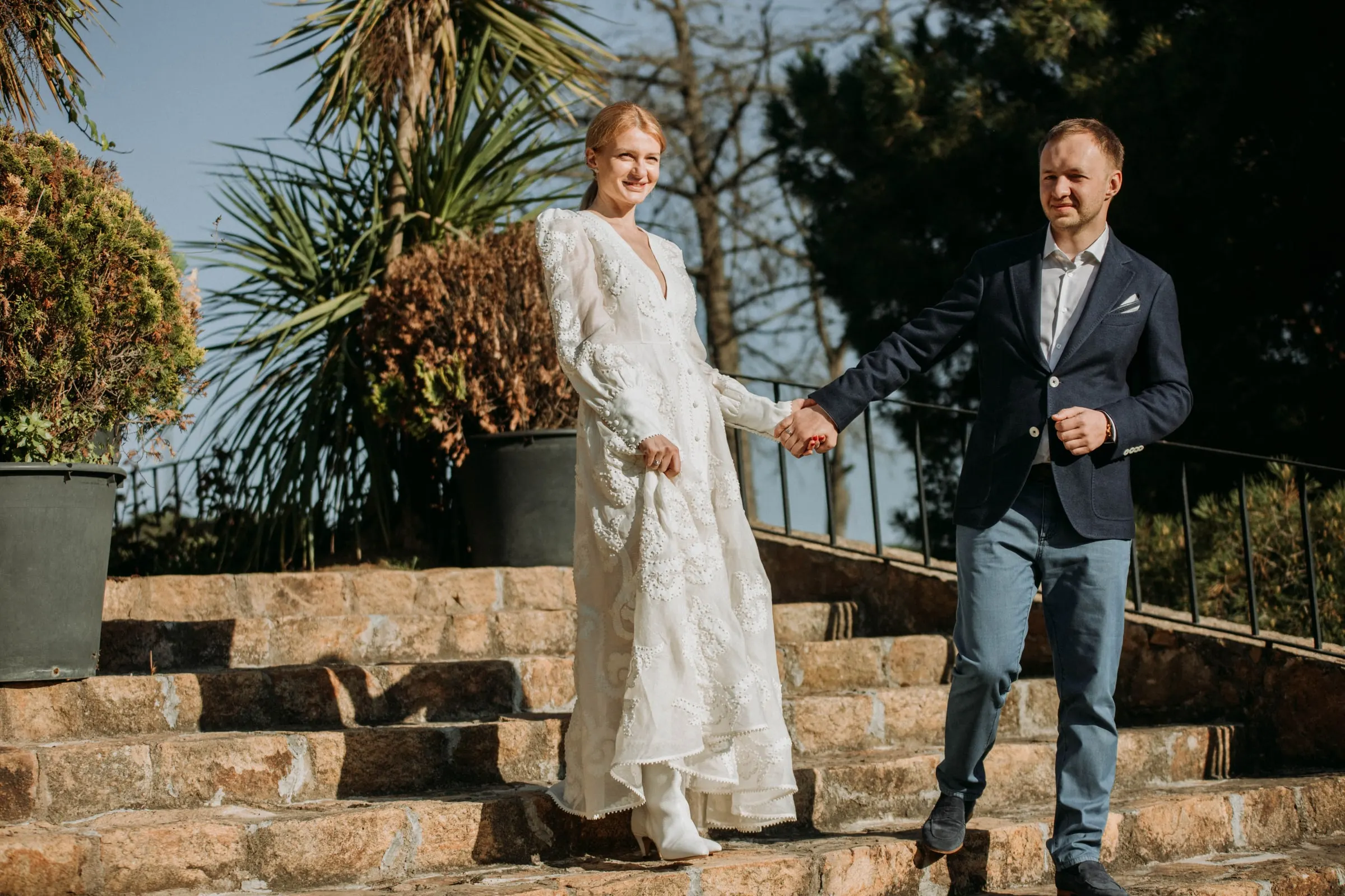 Bride and groom walking hand in hand down the stone steps of the garden at a masia in Girona
