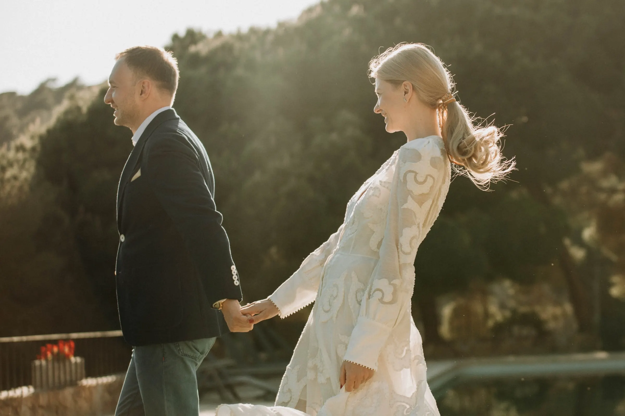 The bride leading the groom by the hand across the sunlit terrace of a masia in Girona