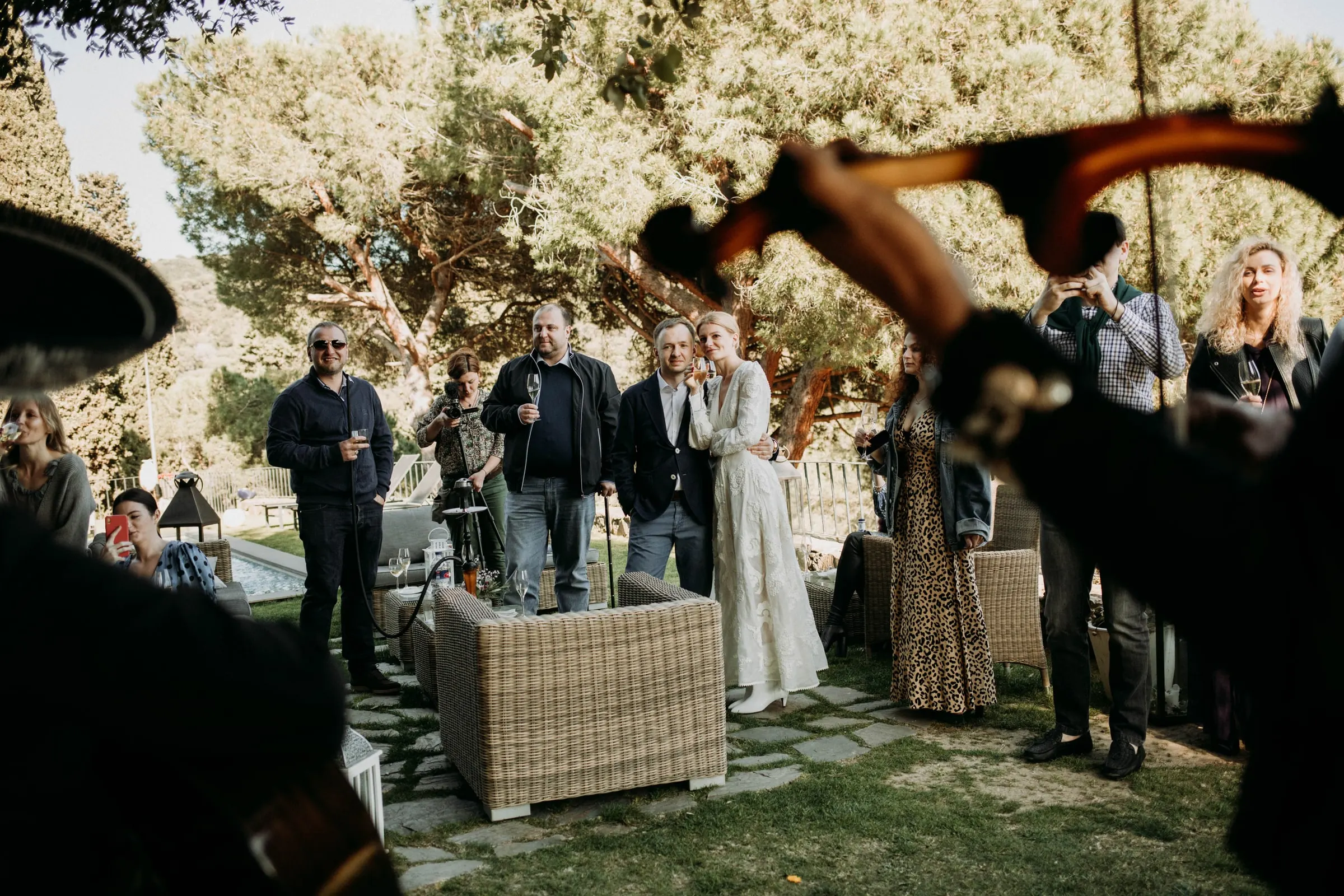 The couple and guests listening to a mariachi violinist in the garden of a masia in Girona