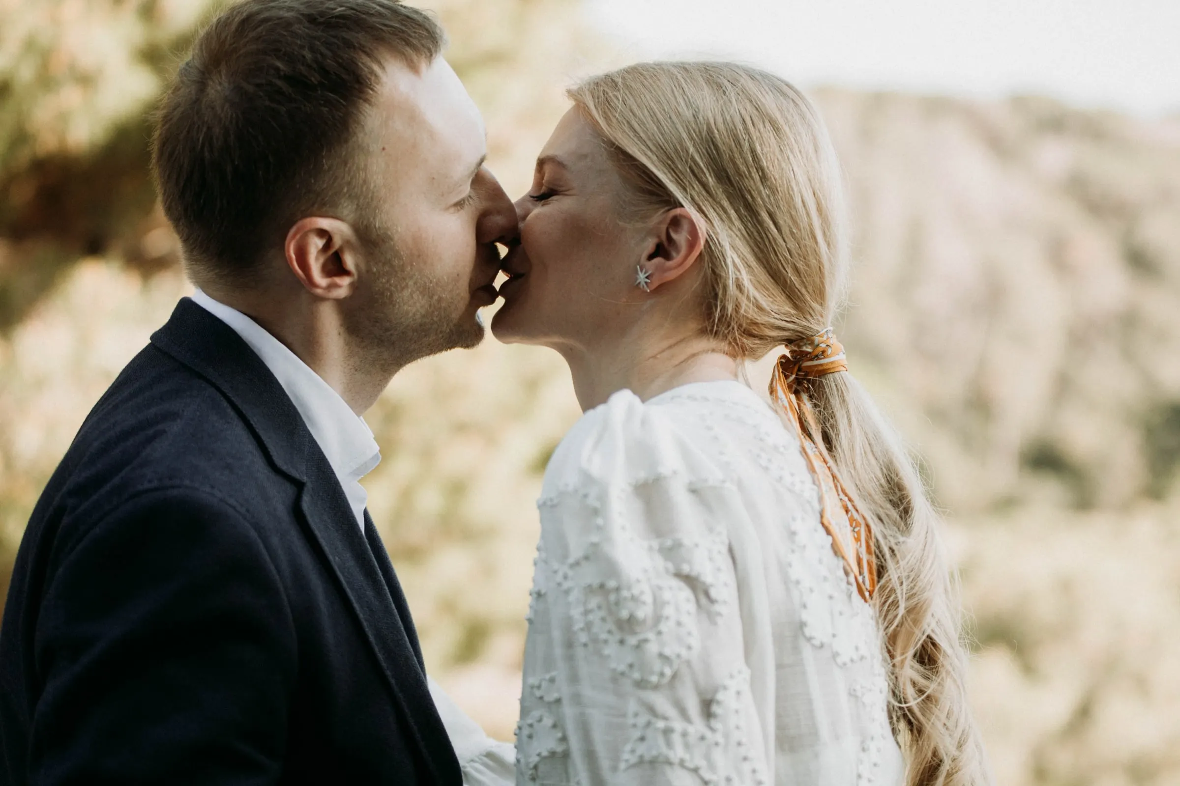 Bride and groom kissing with the wooded hills softly blurred behind, at a masia in Girona