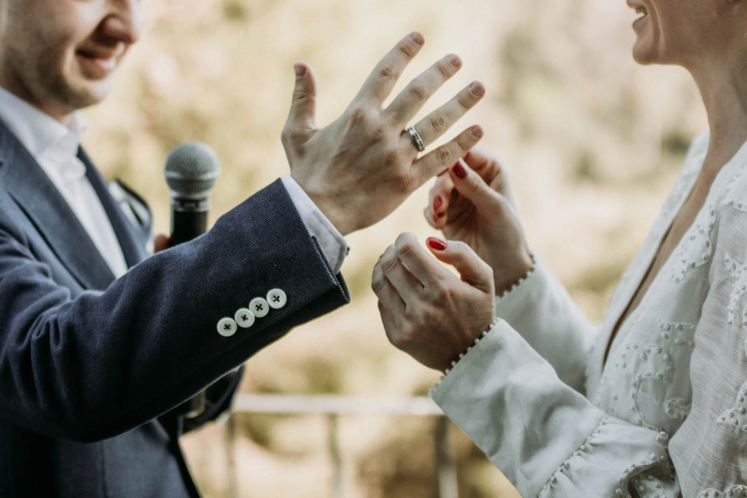 Close-up of the groom showing his wedding ring as the bride holds his hand, at a masia in Girona