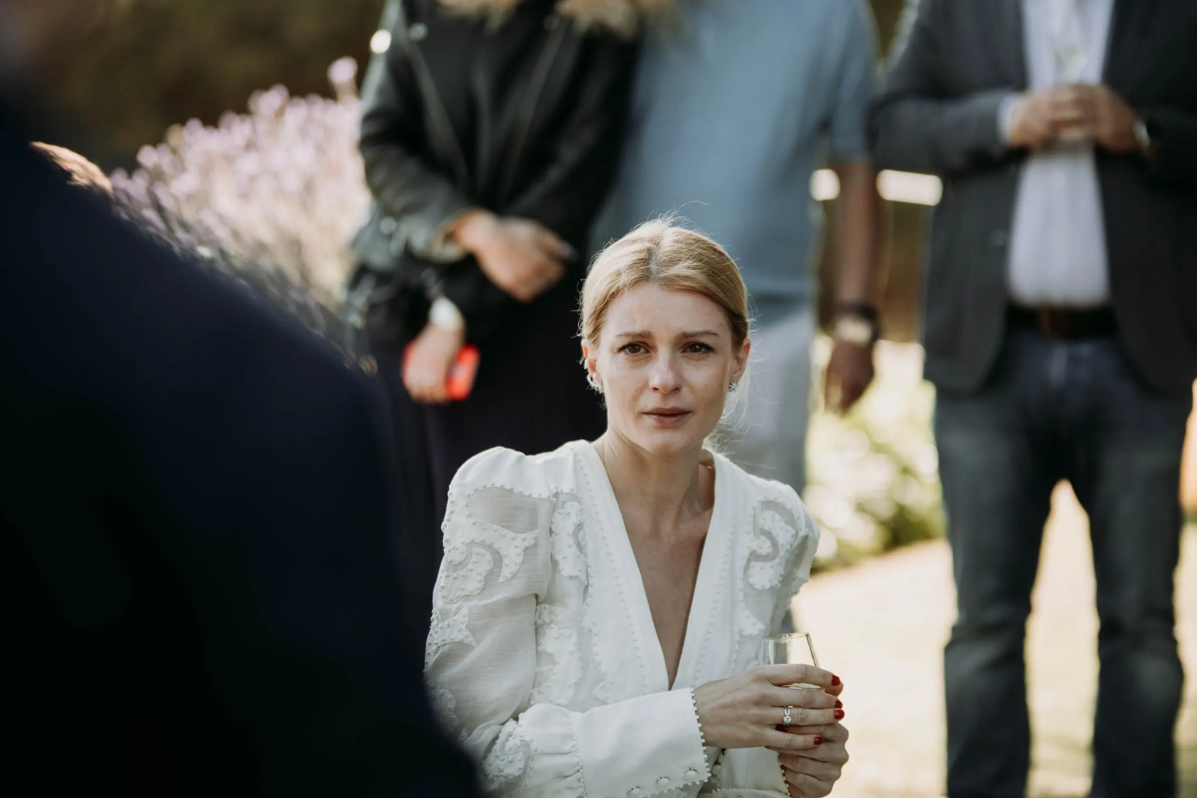 The bride moved to tears, glass in hand, surrounded by guests at a masia in Girona