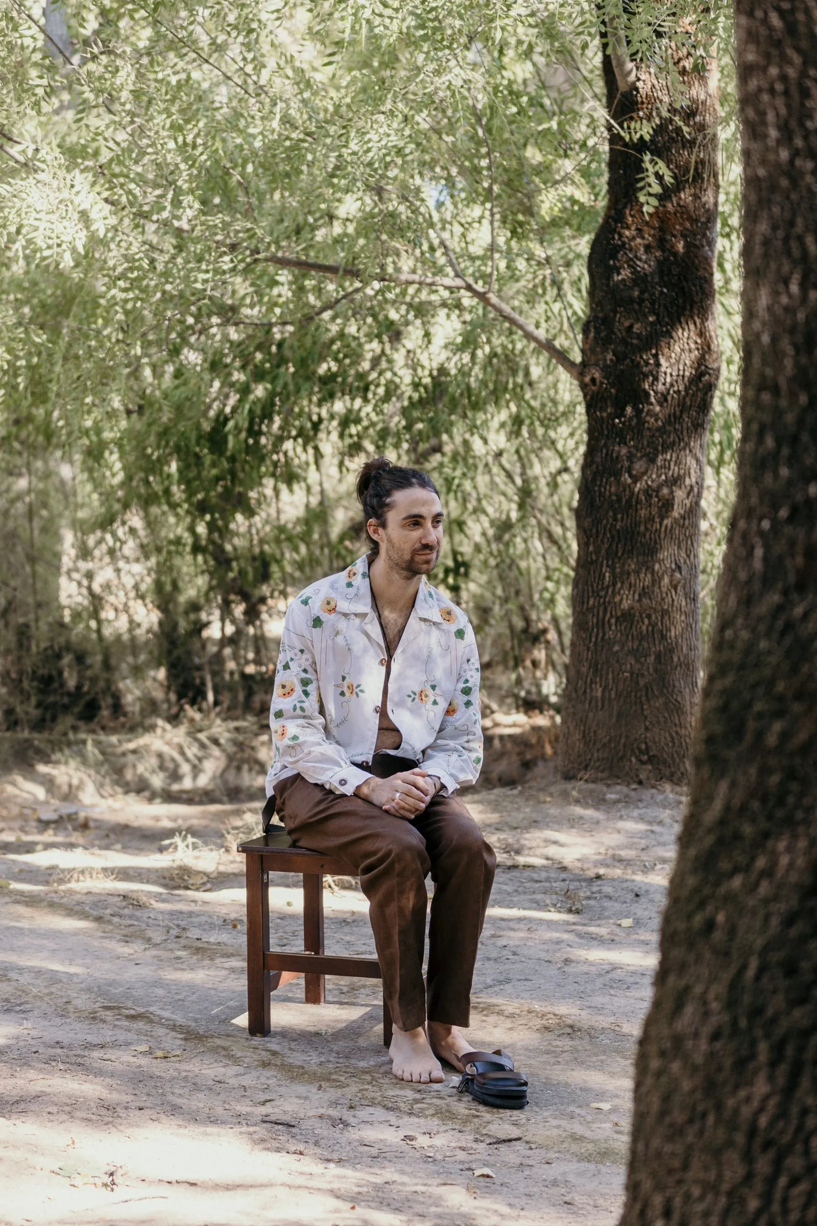 Groom sitting on a wooden chair under the trees at Molino La Flor, Jimera de Líbar