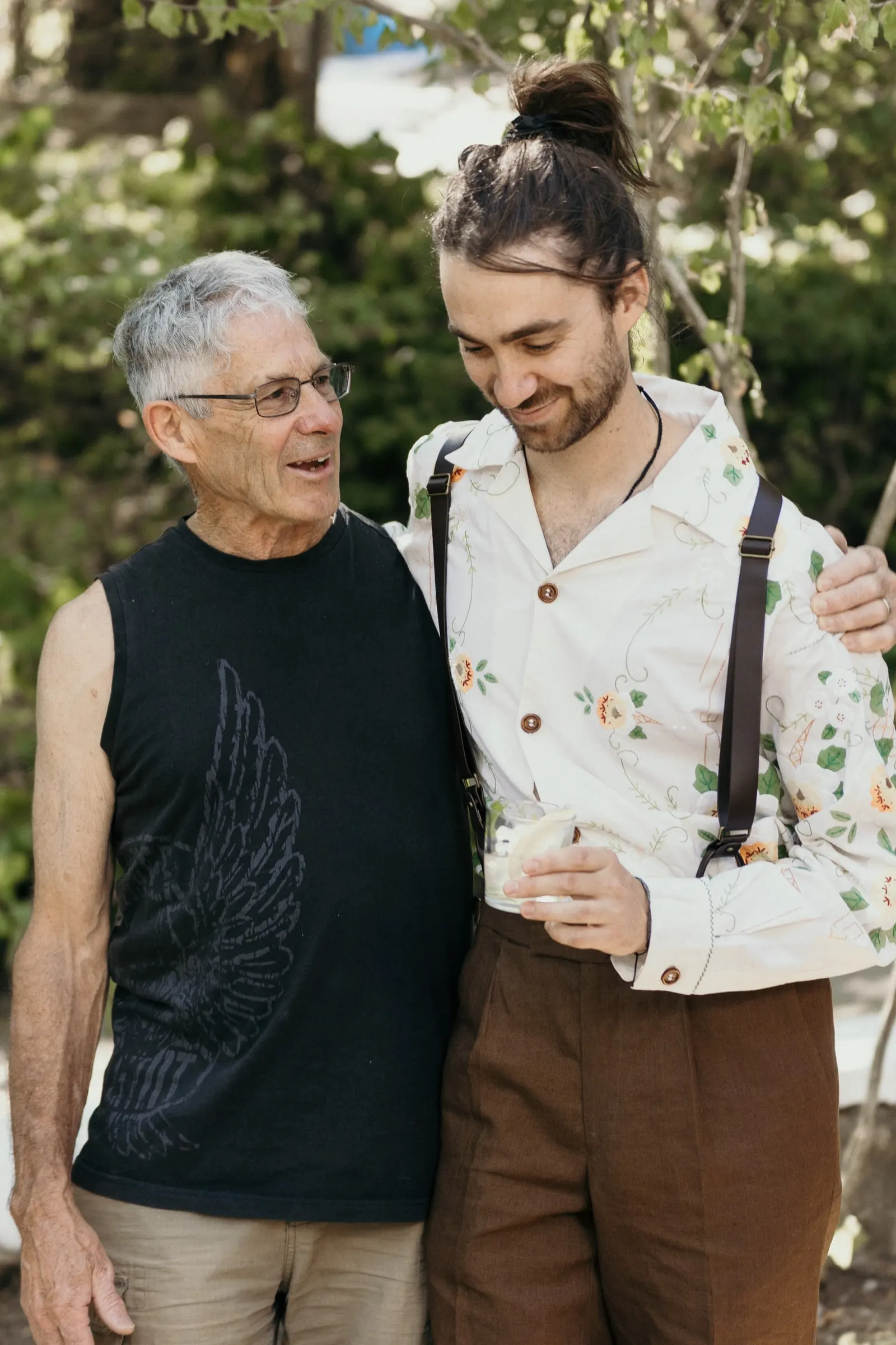 Groom hugging an older man in a black vest before the ceremony