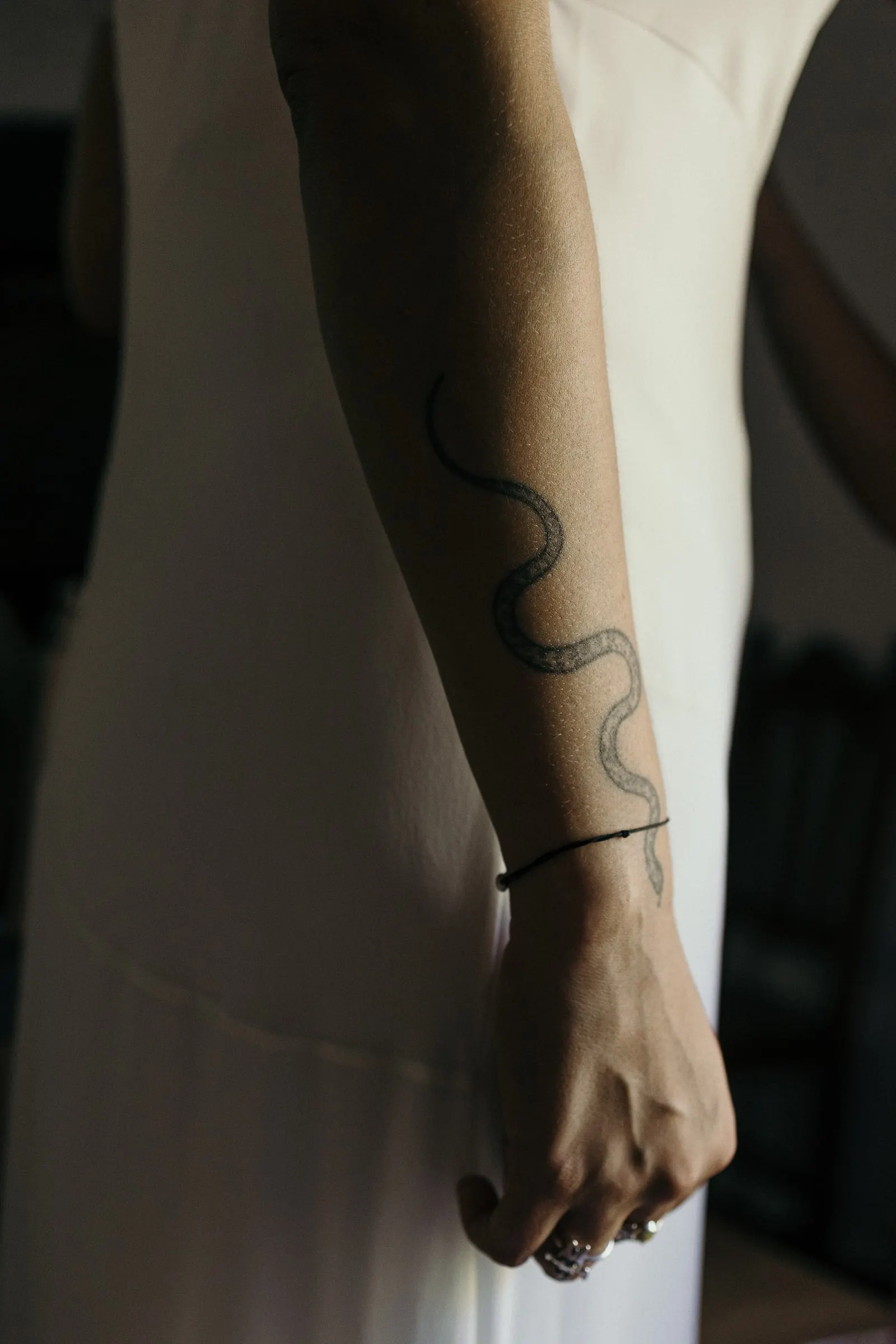 Snake tattoo on the bride's arm against her white silk dress