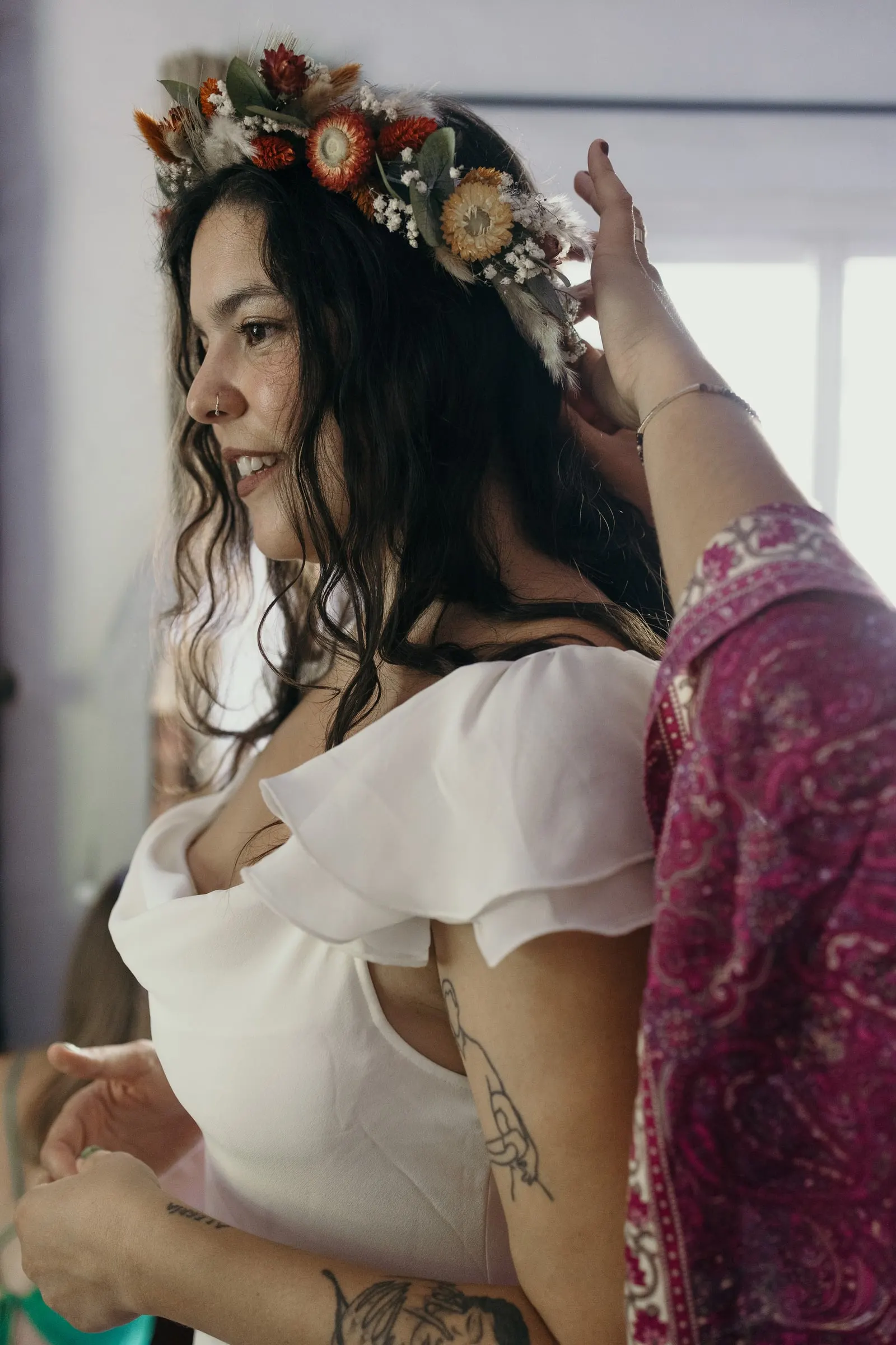 Friend placing a dried-flower crown on the bride's hair