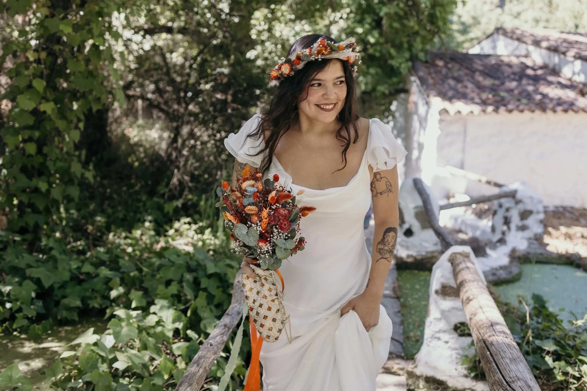 Bride laughing by the wooden rail of the mill stream with a whitewashed mill house behind, Molino La Flor