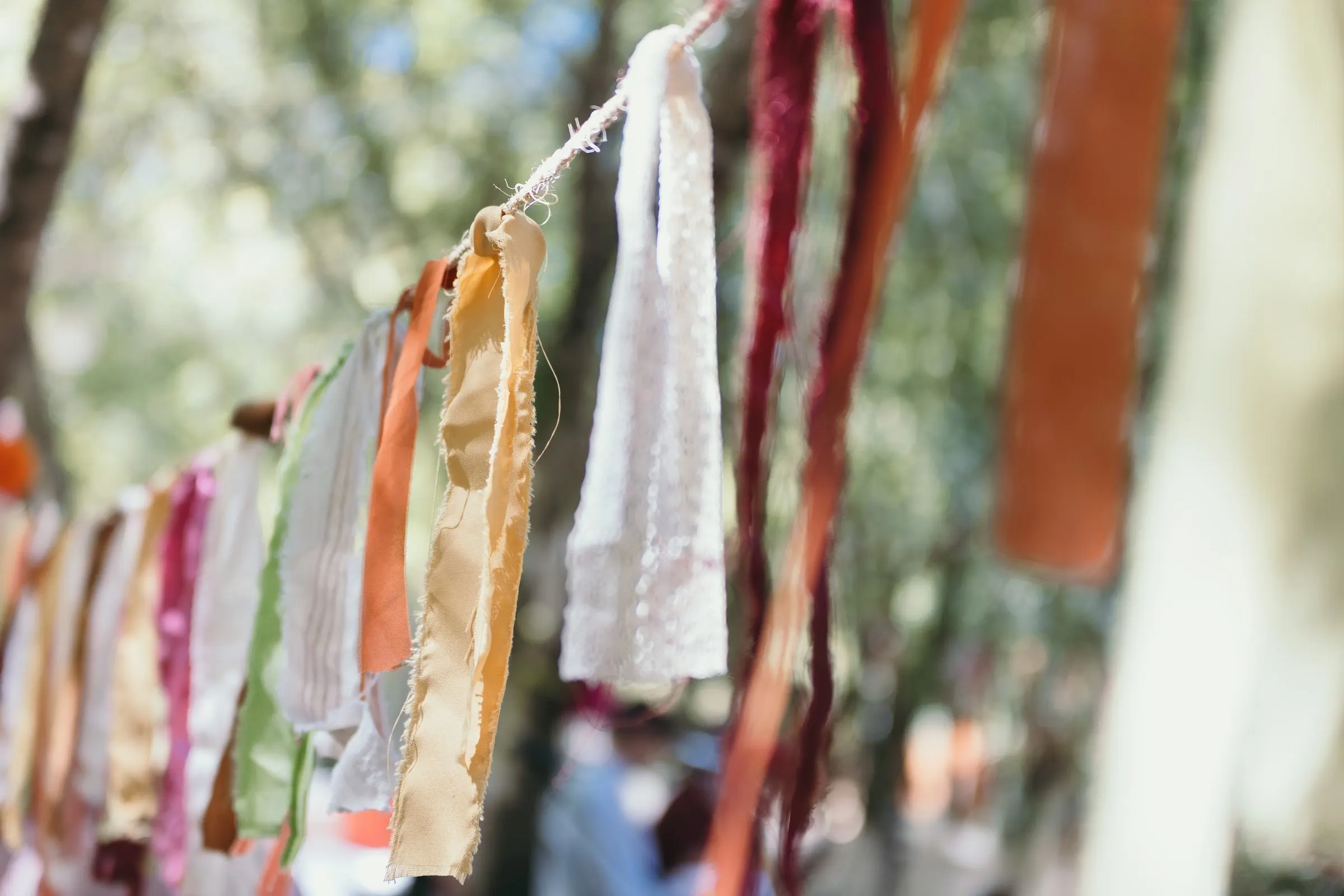 Close-up of colourful fabric ribbon garlands hanging over the ceremony
