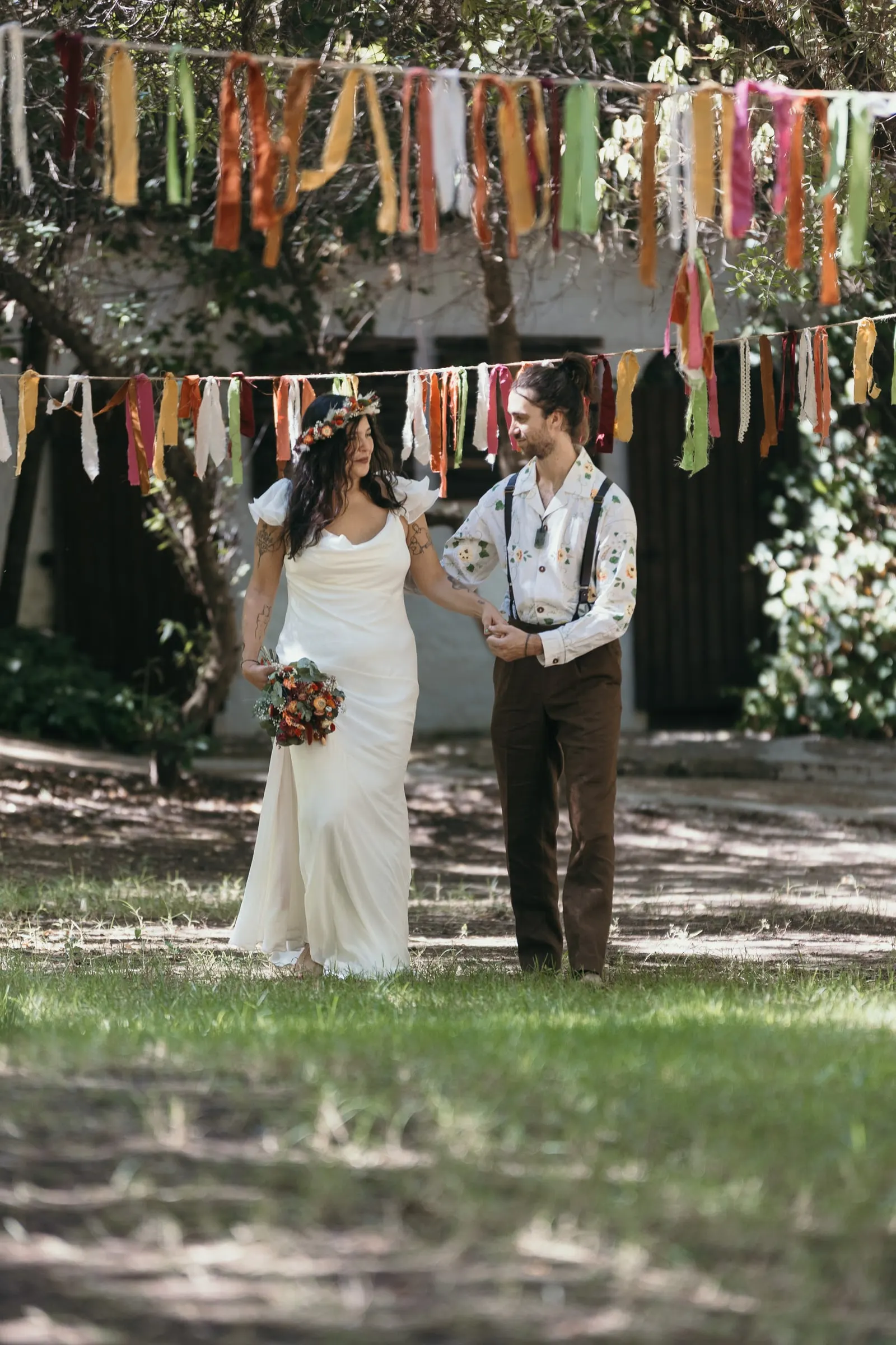 Bride and groom walking together under the ribbon garlands to their ceremony