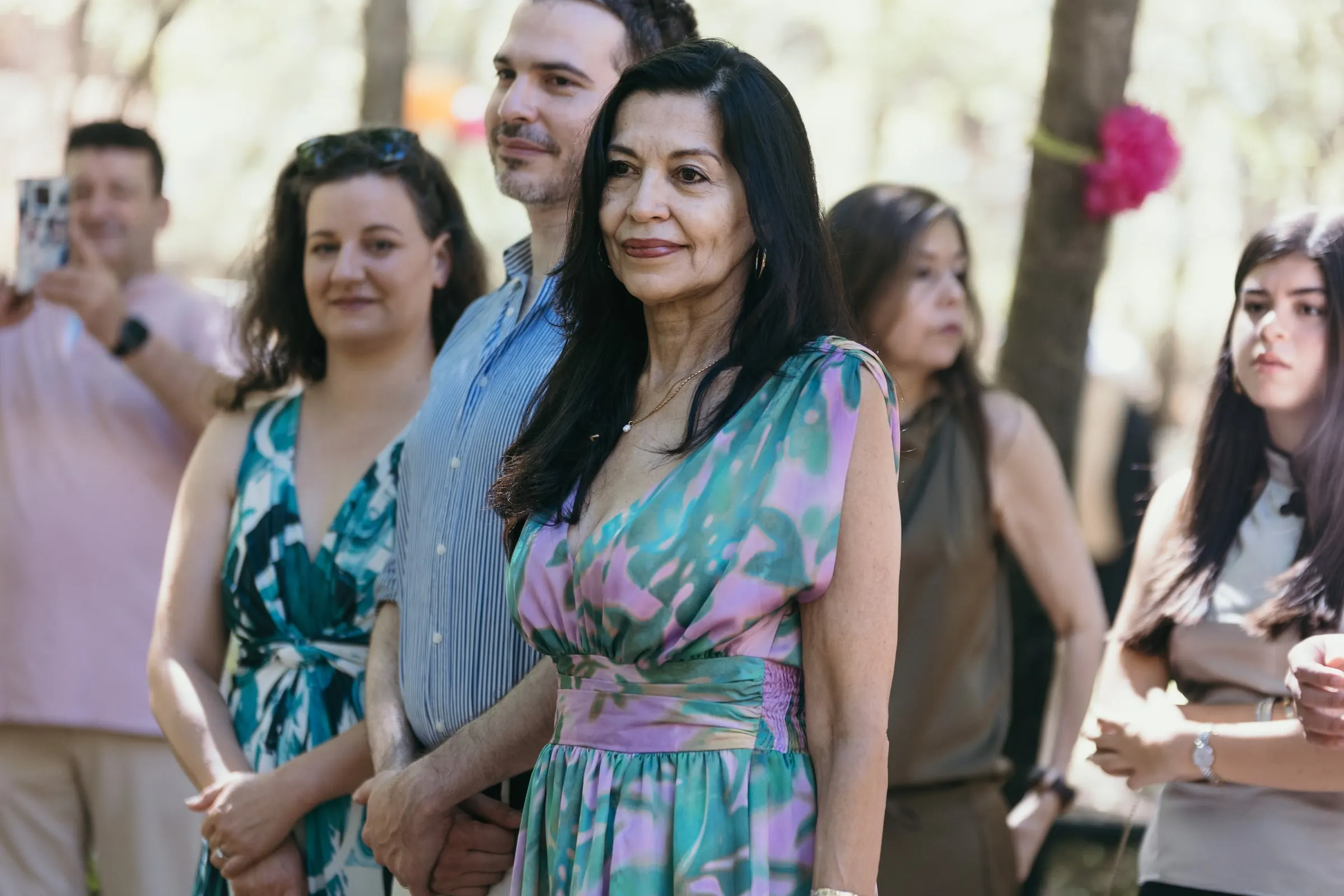 Guests standing to watch the couple arrive under the trees