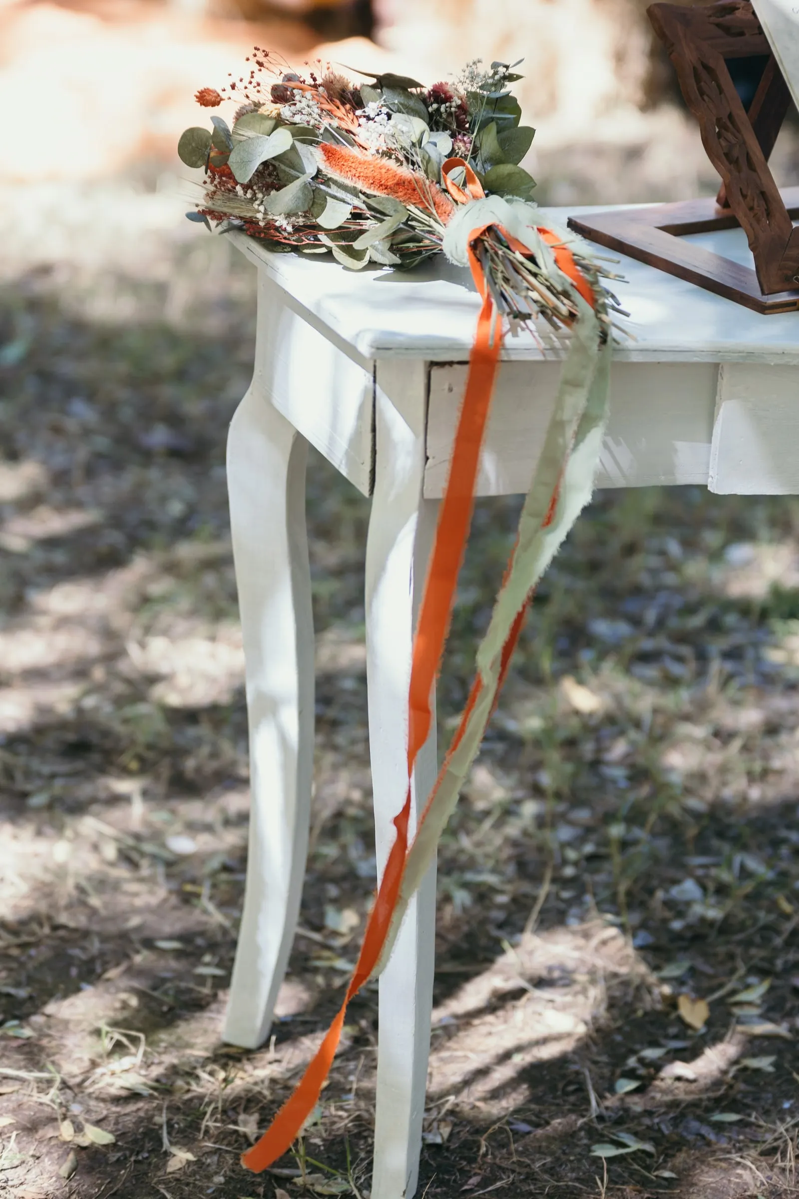 Dried-flower bouquet with orange ribbons on a white ceremony table
