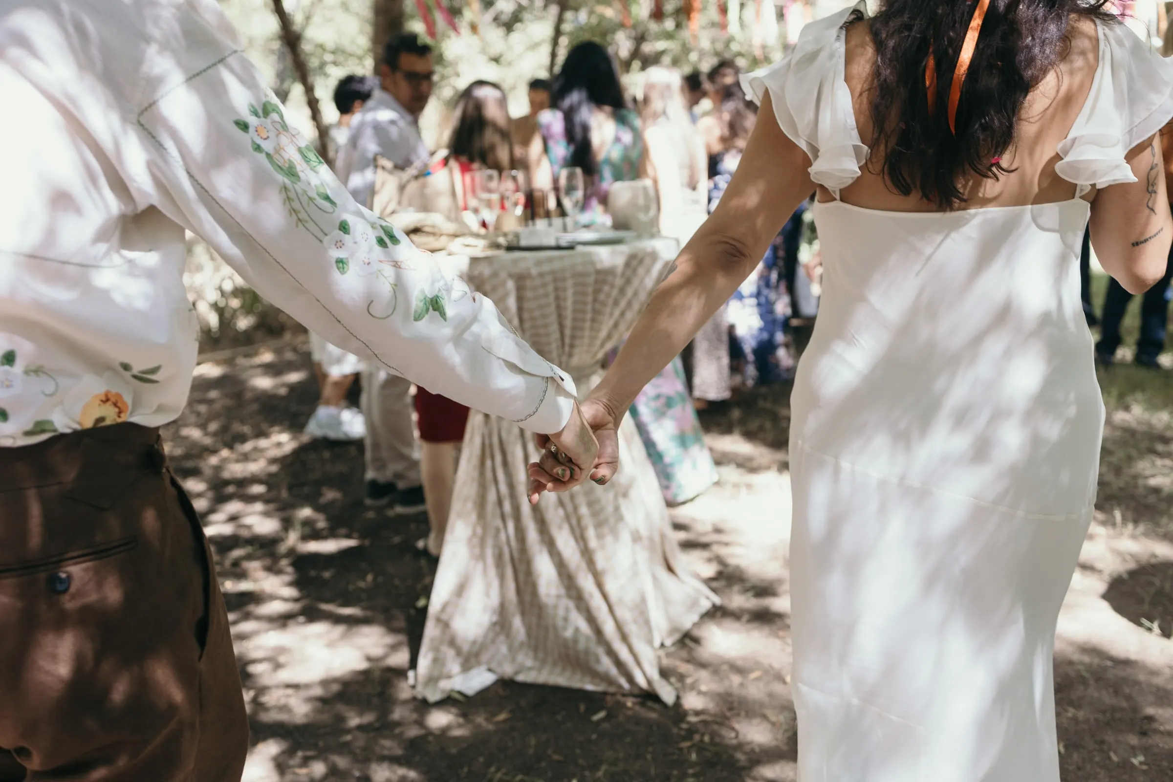 Bride and groom holding hands as they walk among their guests